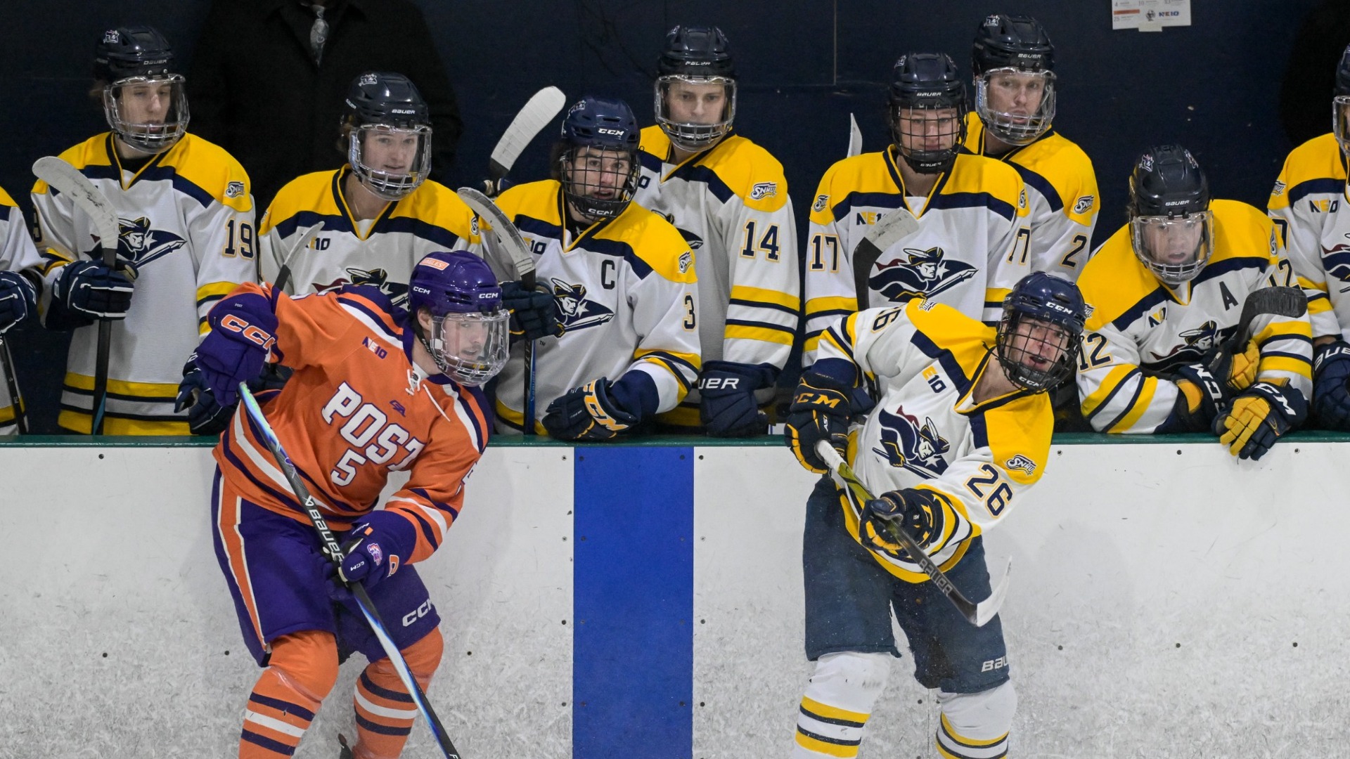 Brendan Lynch sends a puck forward in front of the SNHU bench