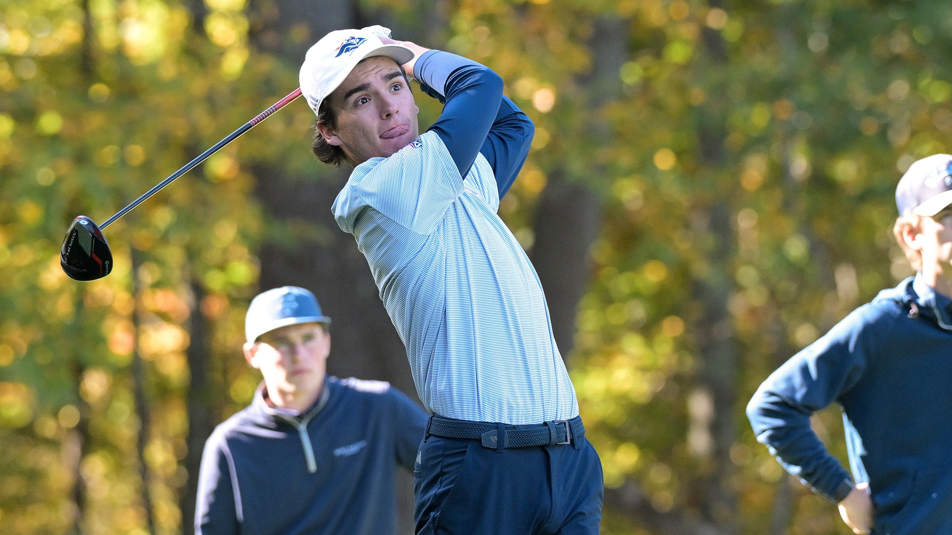 Sam Maurice hitting his drive with a pair of opponents in the background