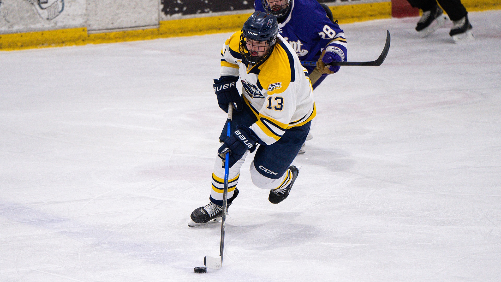 Kurt Watson skating with the puck, with a defender chasing in the background