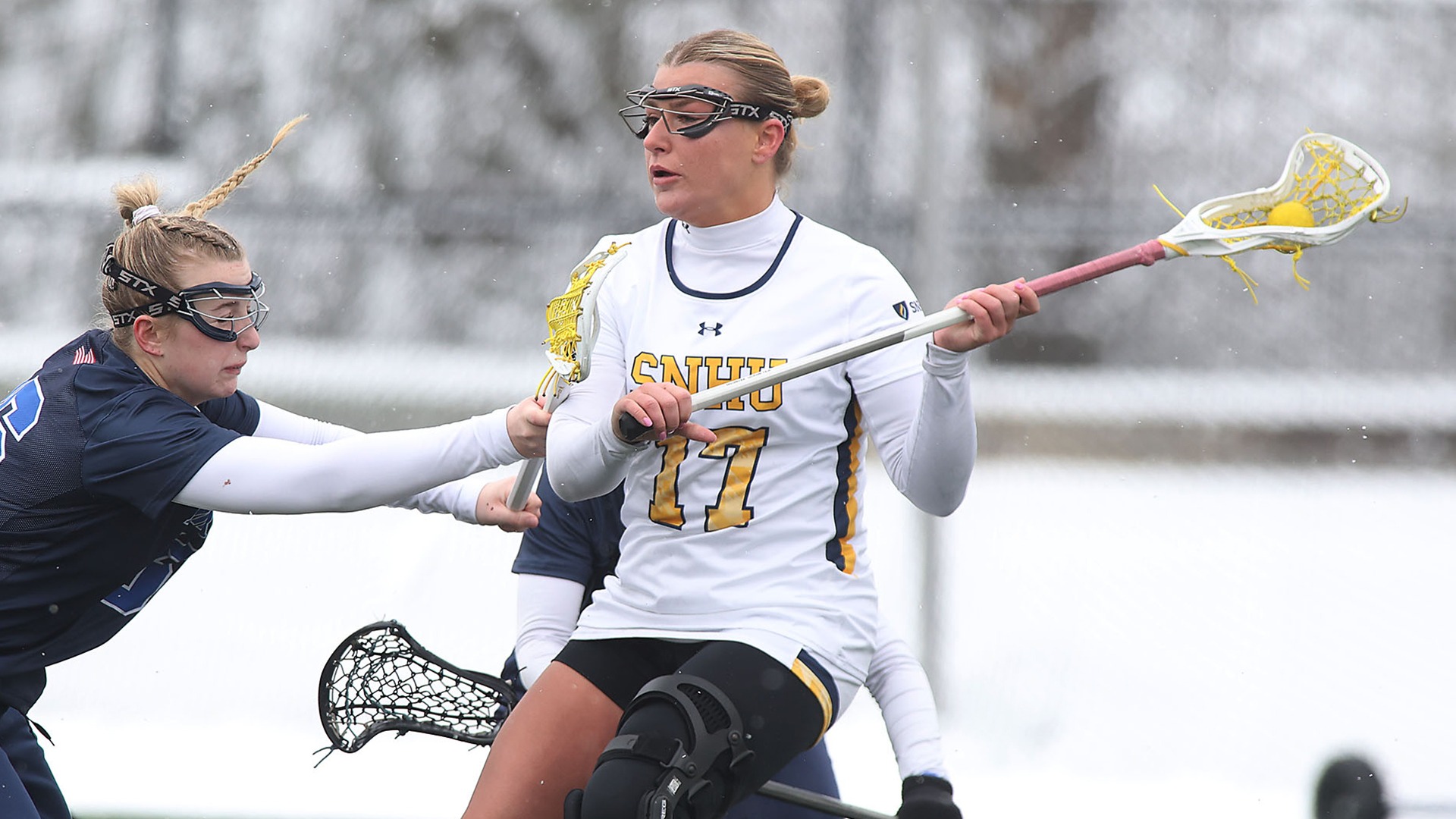 Brynn Goulet cradling the ball in her stick, while being checked by a defender