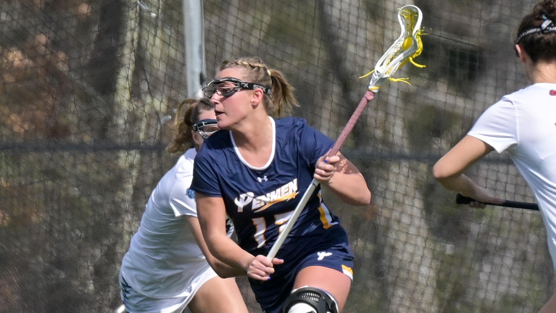 Brynn Goulet with the ball in her stick and defenders on either side