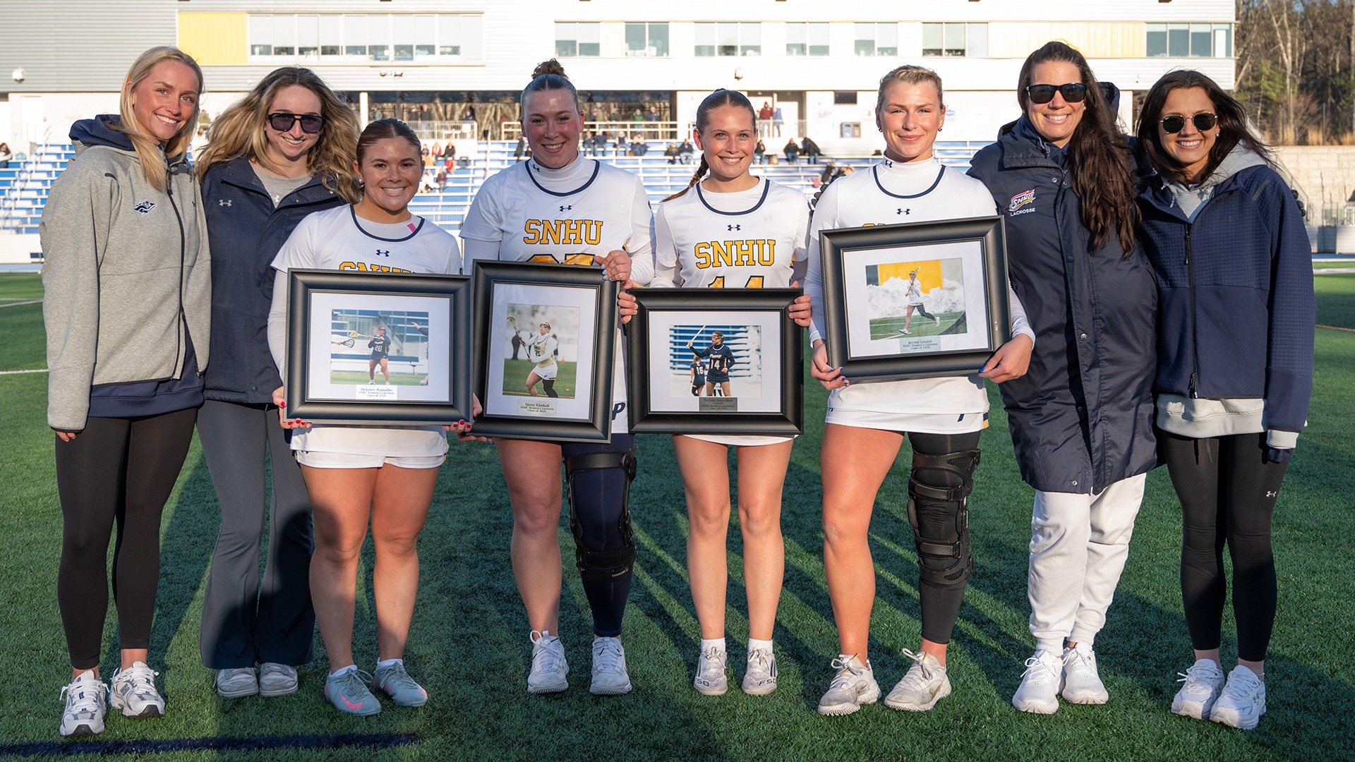 SNHU women's lacrosse seniors posing with coaches following the 2026 Senior Night ceremony