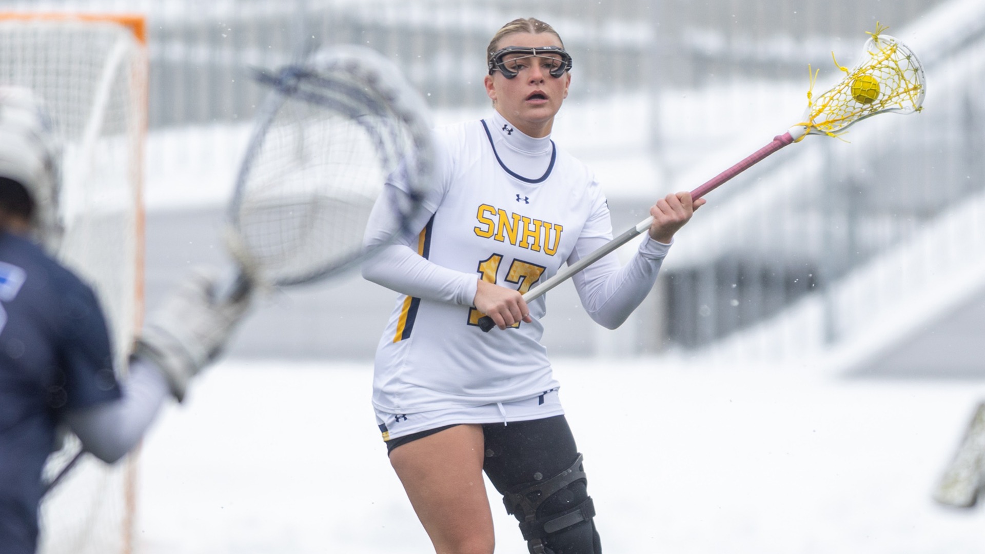 Brynn Goulet holding the ball in her stick with the opposing goalkeeper in the foreground