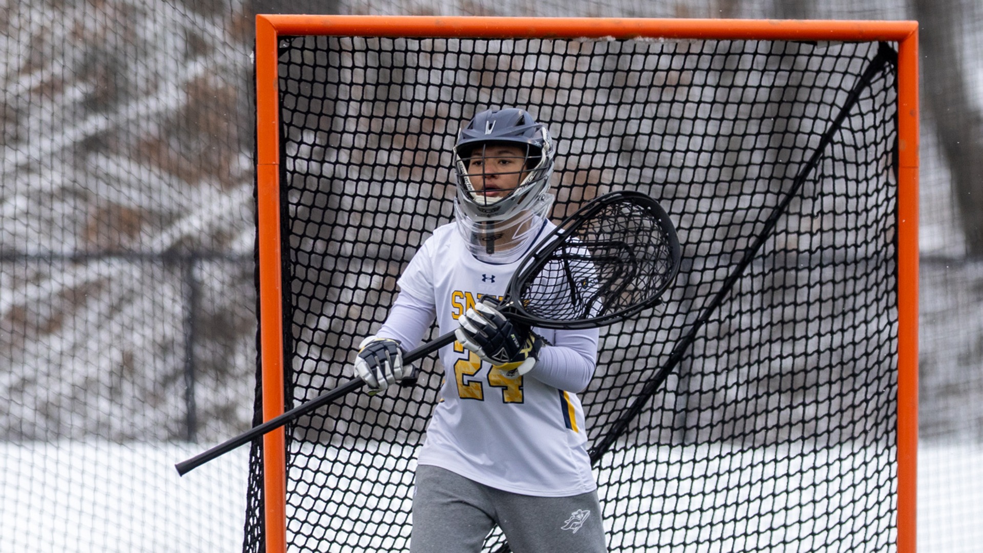 Corrina Moulton standing in the goal wearing her goalie helmet and holding her stick