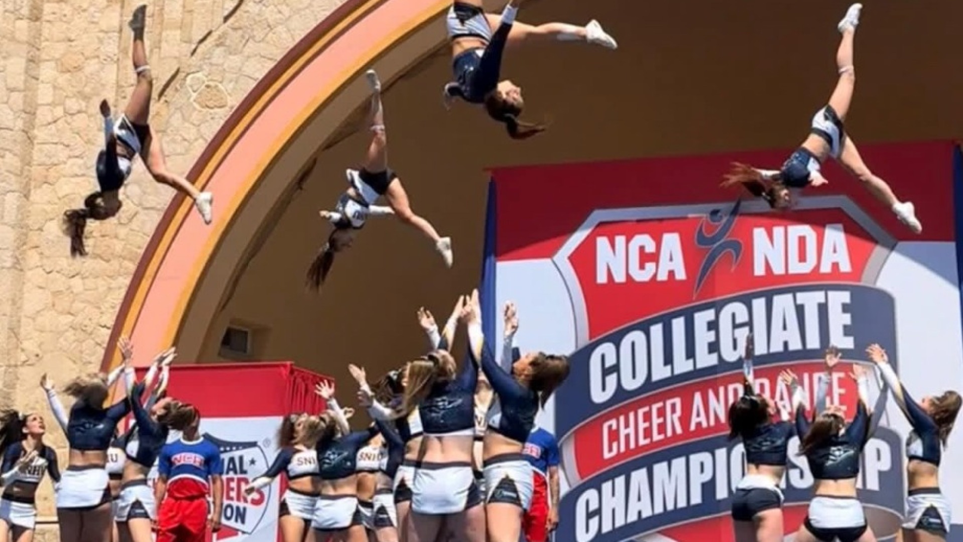 Three athletes are shown in the air during the routine on Daytona Beach Bandsheel