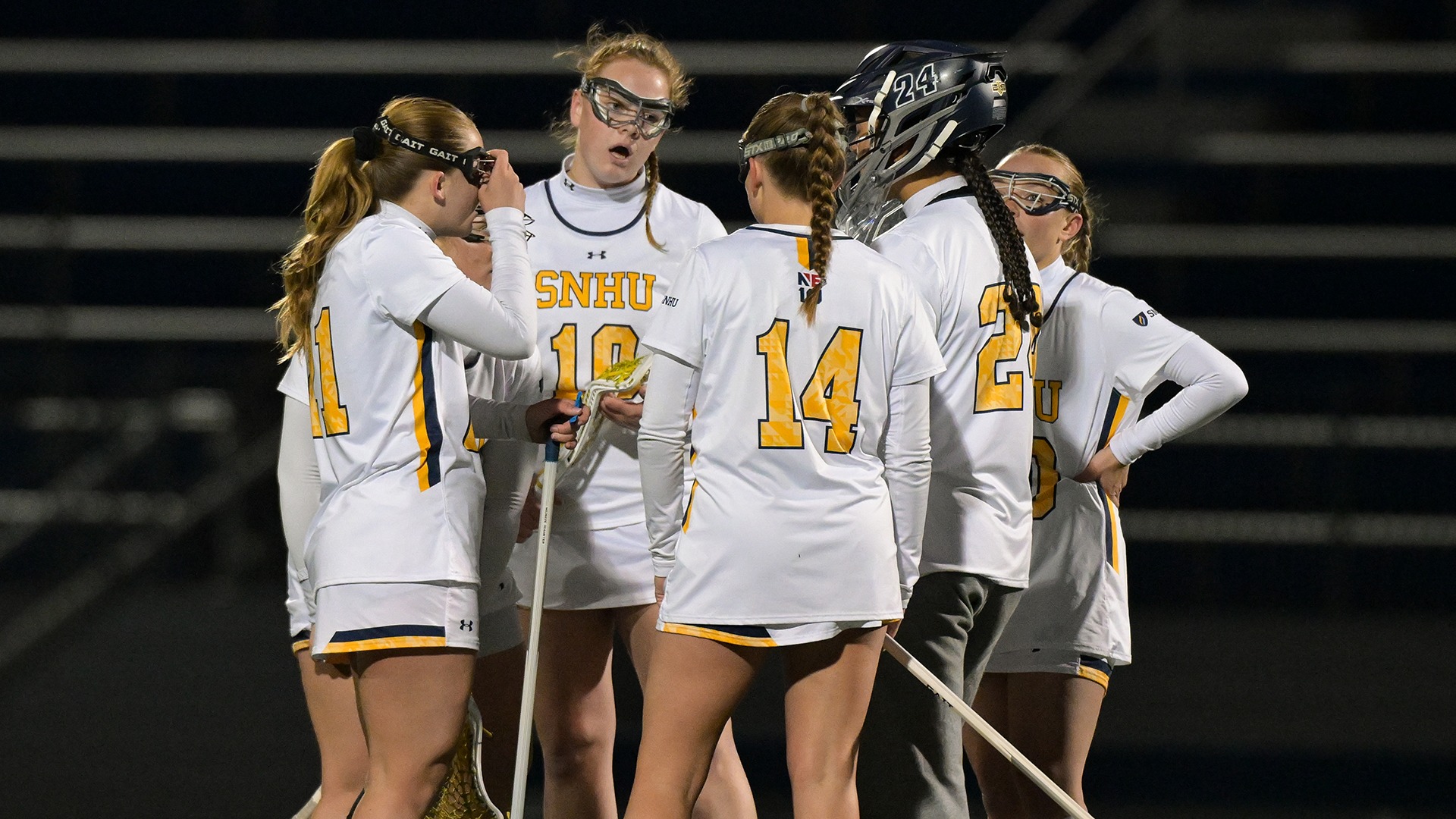 members of the SNHU women's lacrosse team in a huddle during the game