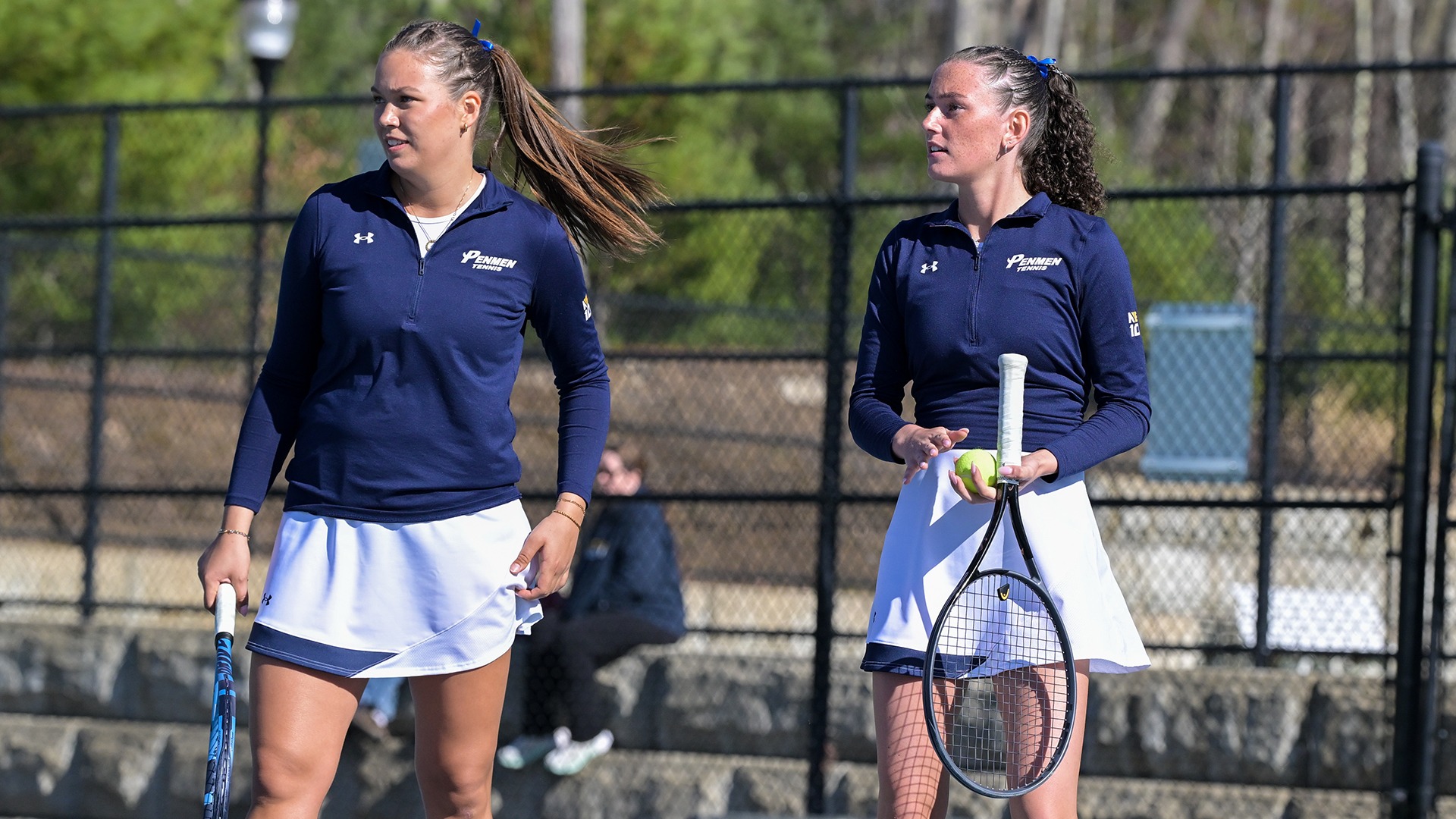Eyglo Armannsdottir and Megan Leck standing on the court holding their racquets during a break in their doubles match
