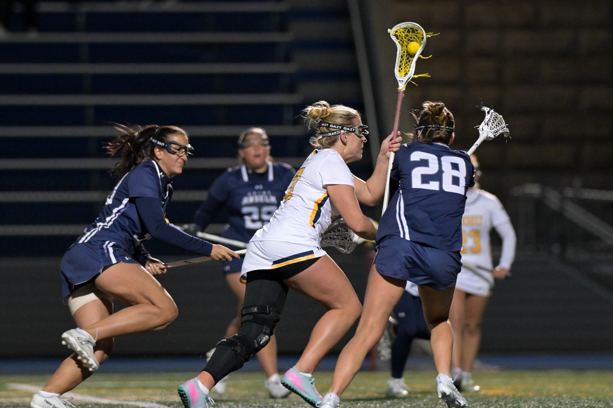 Brynn Goulet driving to the net with the ball in her stick, flanked by defenders