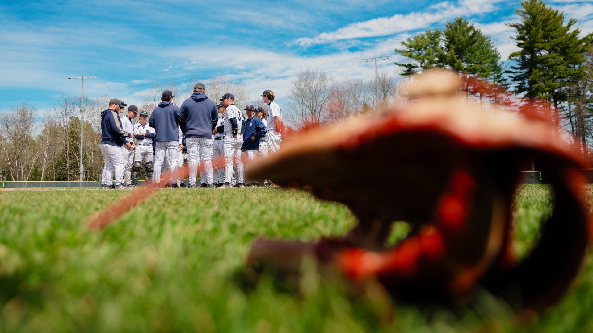 Team Huddle with Baseball Glove in Foreground
