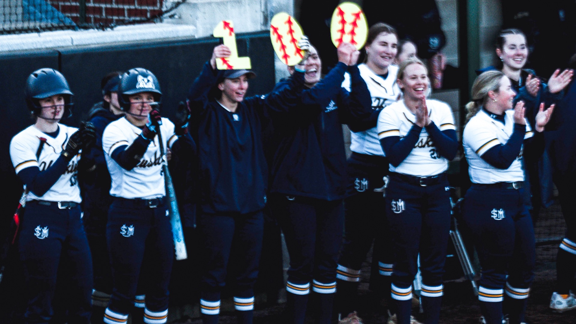 Husky softball players celebrate Olivia Levasseur's 100th career hit