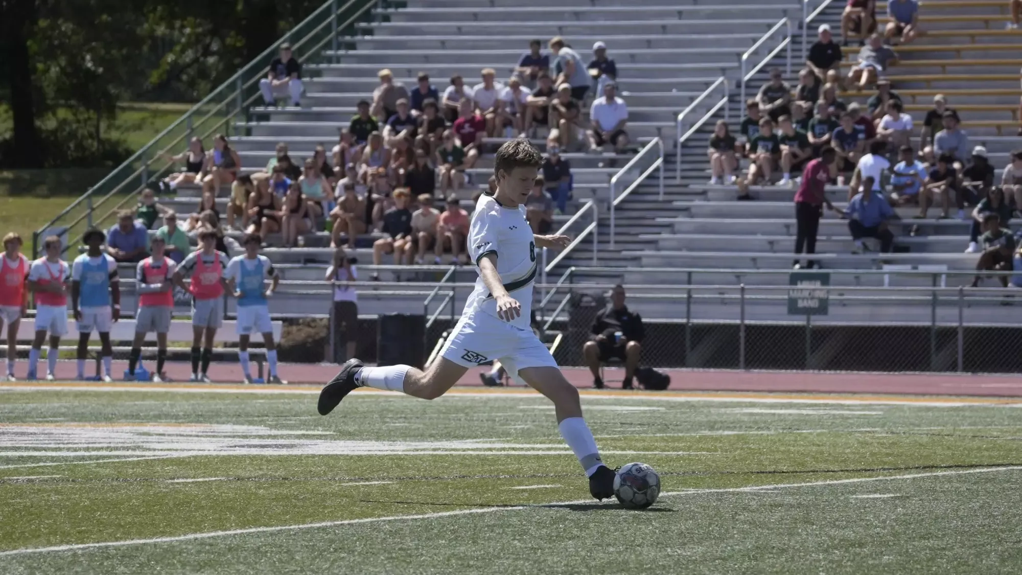 Luke Giesing of Missouri S&T men's soccer is photographed kicking the ball during a match at Allgood-Bailey Stadium. He is wearing a white soccer kit.