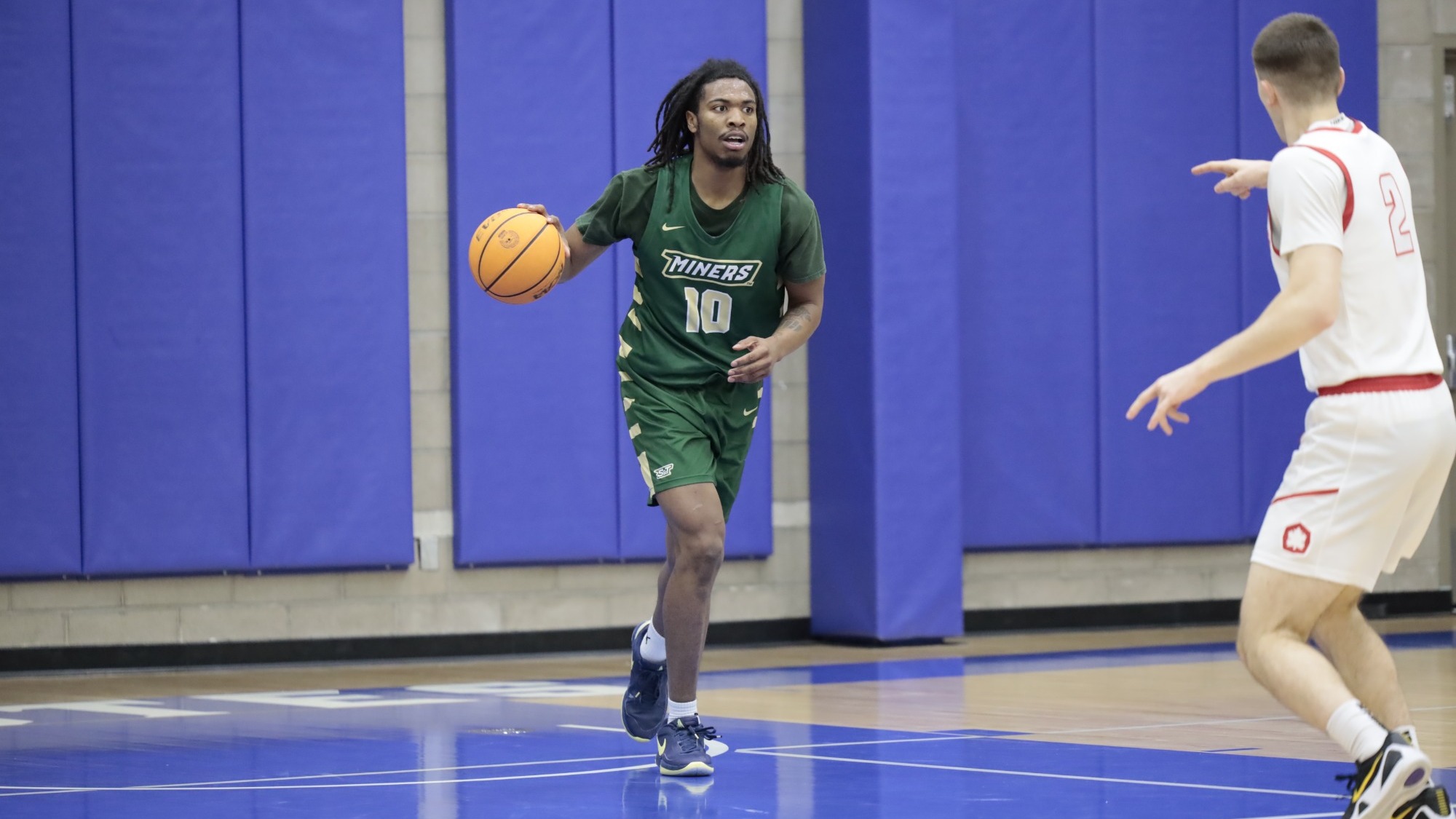 Photo of a men's basketball player dribbling the basketball and looking up the court