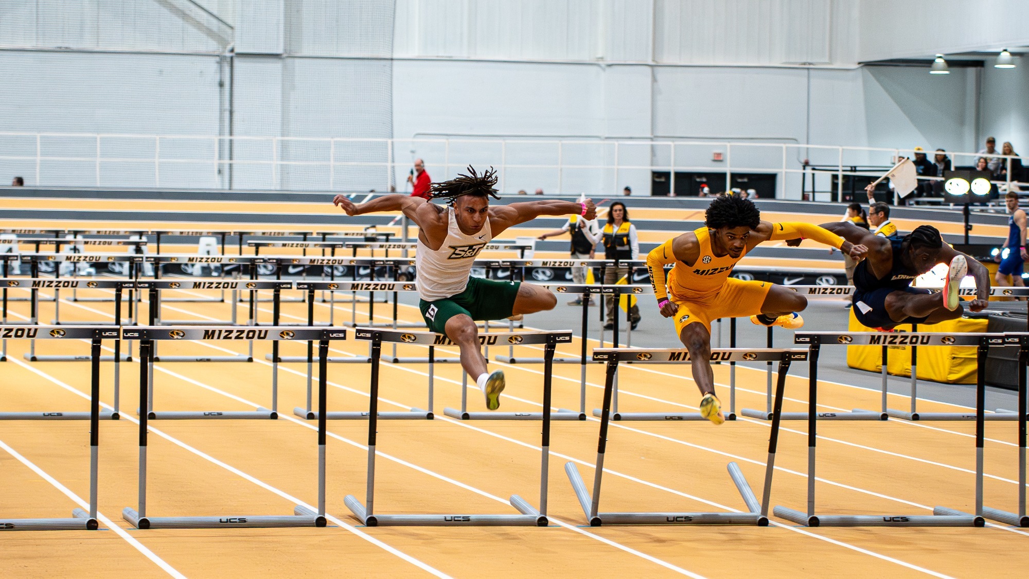 Louis Yohannes jumping over hurdler competing in the 60m hurdles with a mizzou competitor to the left of him at the Show Me Showdown hosted by Mizzou.