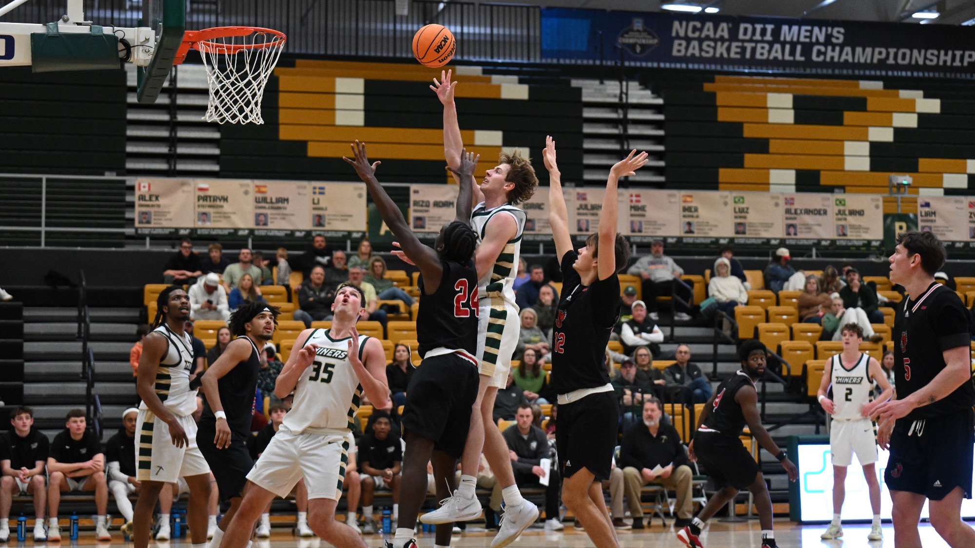 Missouri S&T men’s basketball player Andrew Young jumping and shooting the basketball one handed from in the paint while surrounded by Jewell defenders in the paint