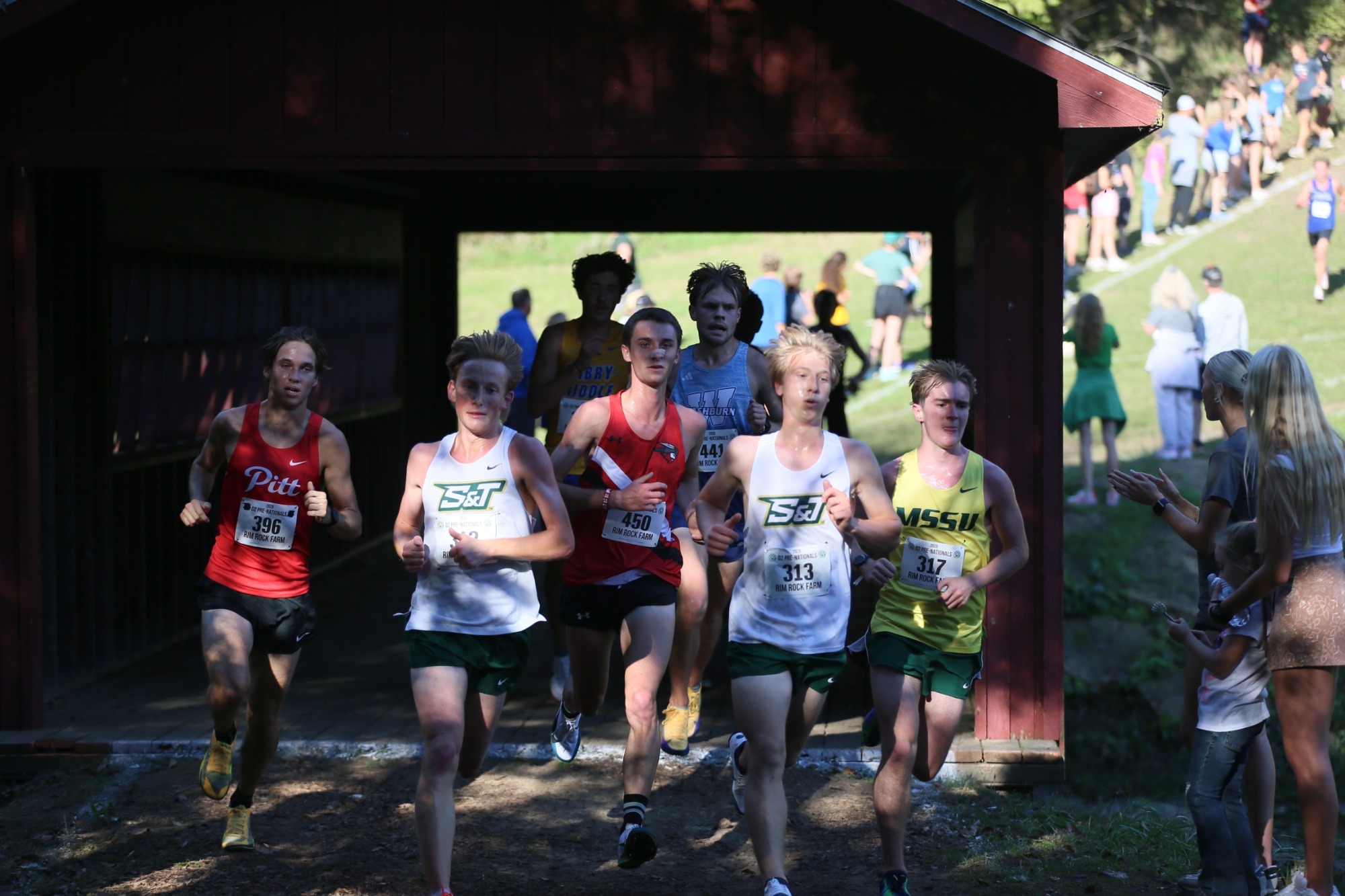 Two MXC S&T athletes running through a red roof tin tunnel in the NCAA DII Prenationals 