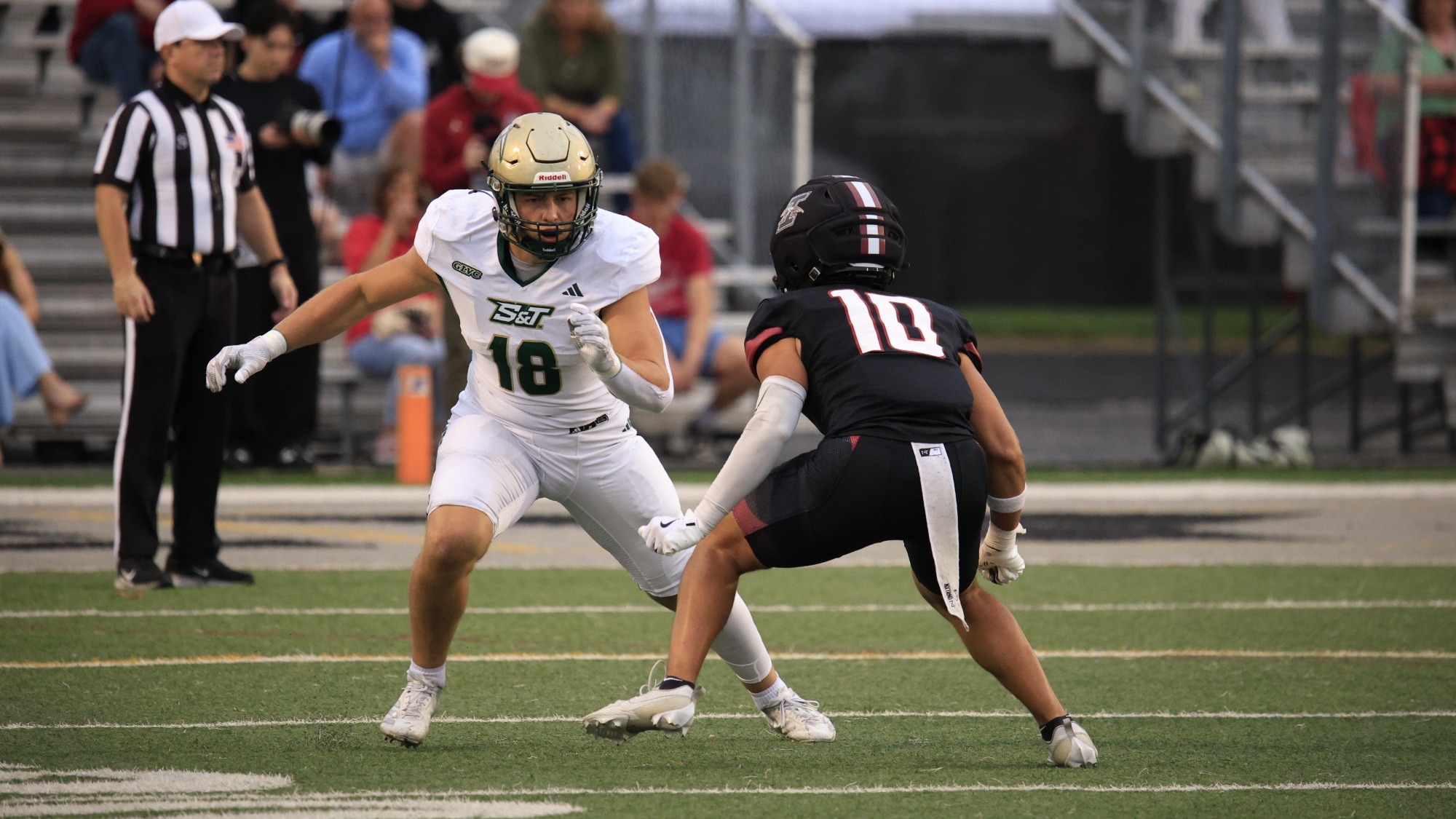 Justis Braden of Missouri S&T football photographed running a route during a game at Indianapolis. He is wearing a white uniform with green trim and a gold helmet.