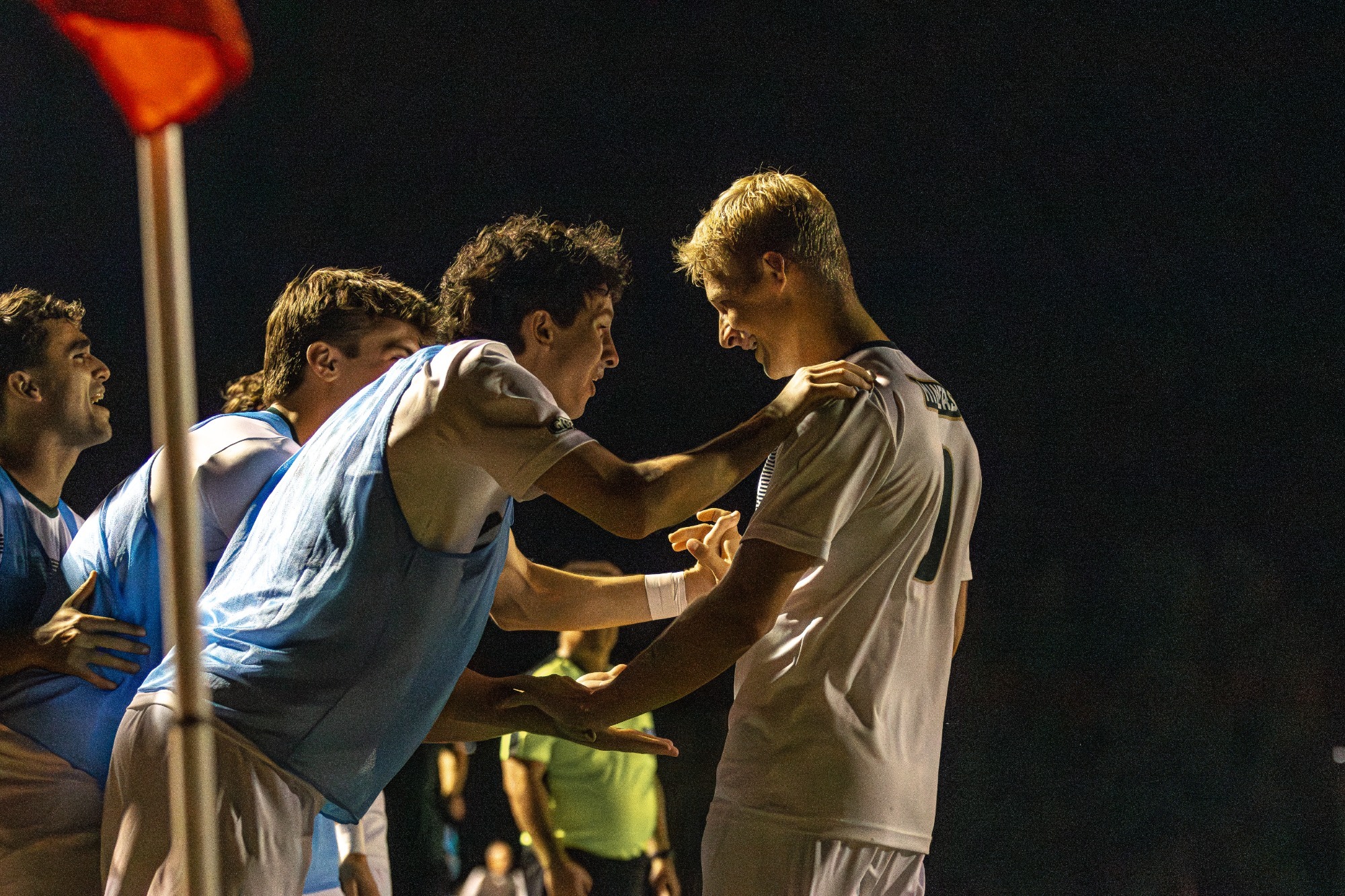 S&T Mike Banasik at the bench celebrating with his teammate grabbing his shoulders and smiling. 