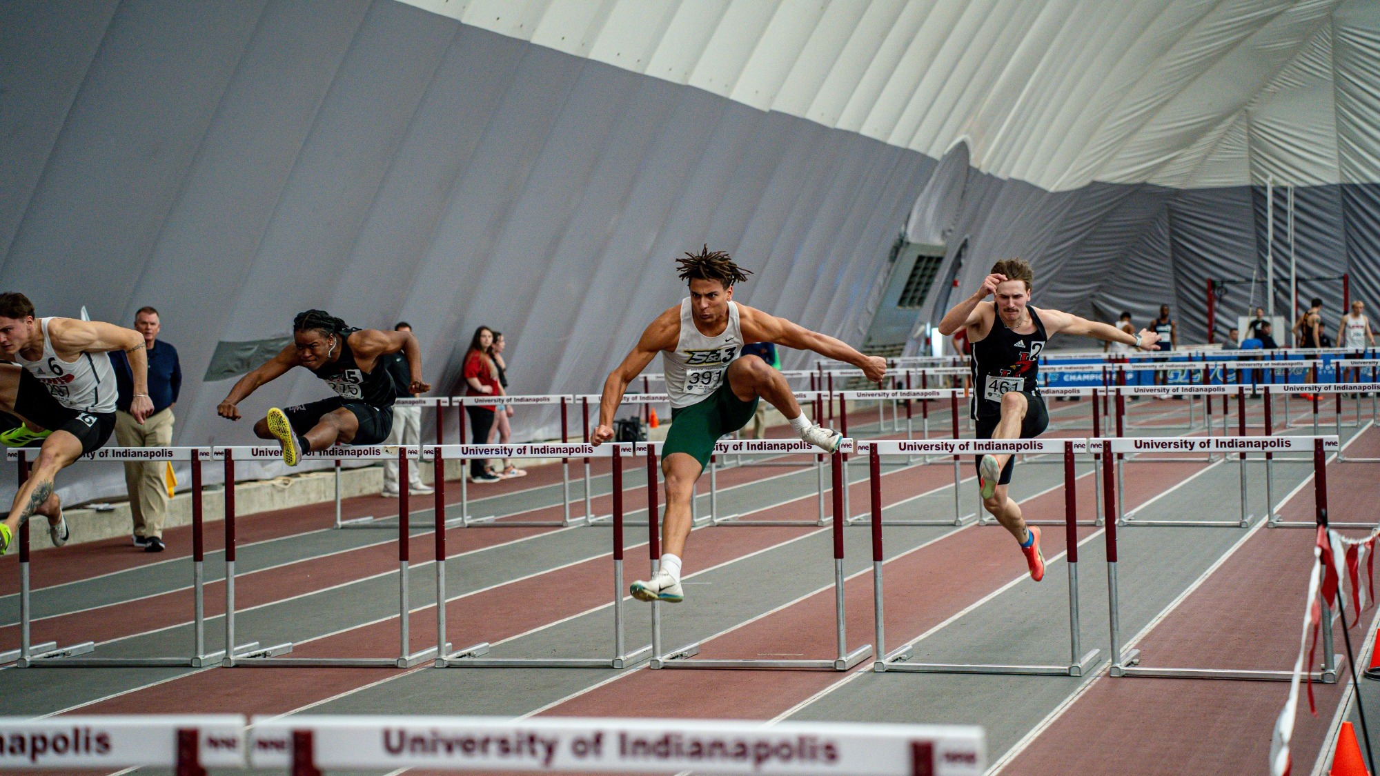 Louis Yohannes jumping over a hurdle in an indoor 