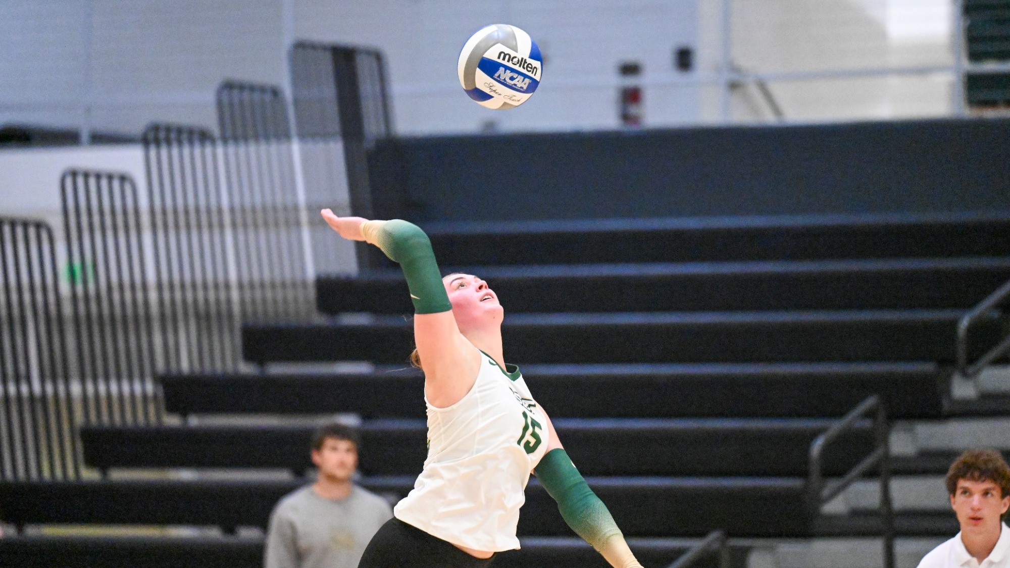 Elly Decker of Missouri S&T women's volleyball photographed wearing a white jersey and serving the ball during a match in Gibson Arena