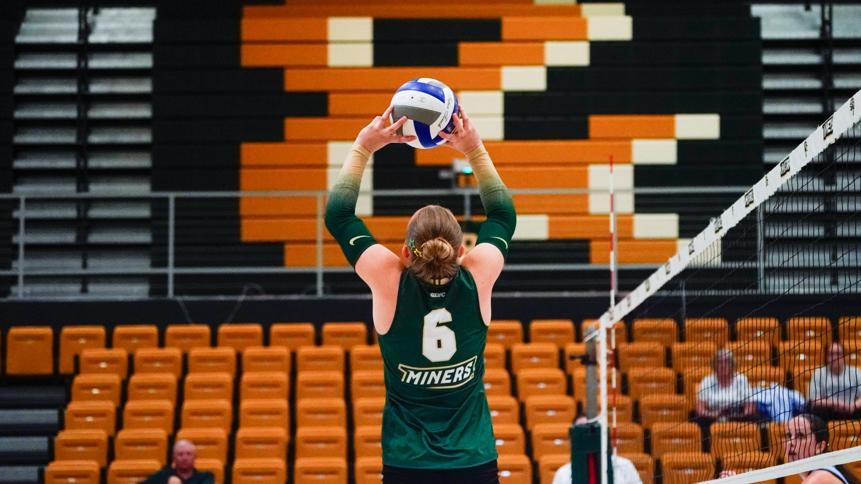 Kaitlyn Brady of Missouri S&T women's volleyball photographed setting the ball during a match in Gibson Arena. She is wearing a green uniform with a white #6 on the back.