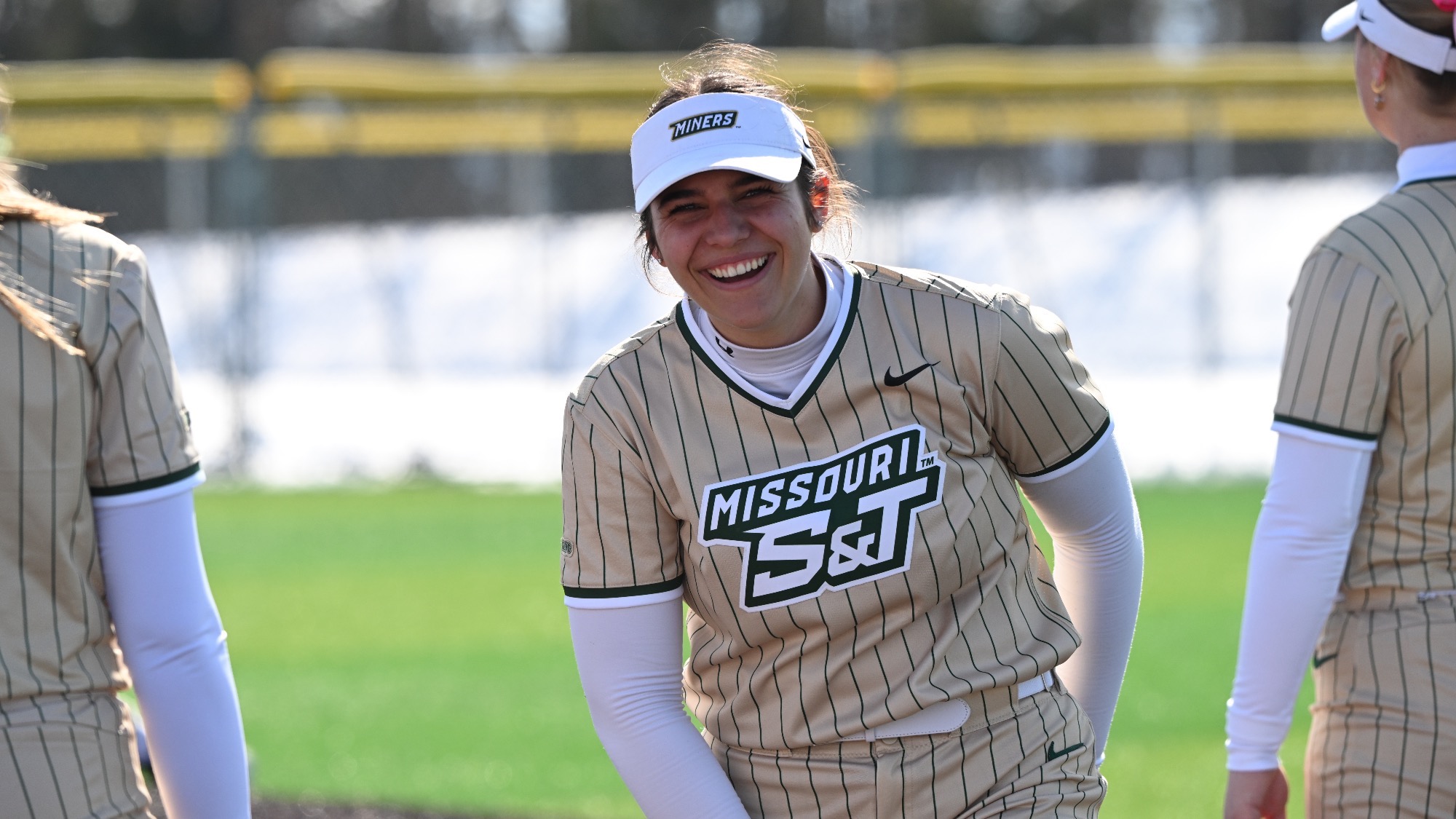 Missouri S&T softball player Alexis Cullinane in gold pin stripes jersey smiling at the Branson Leadoff Classic.