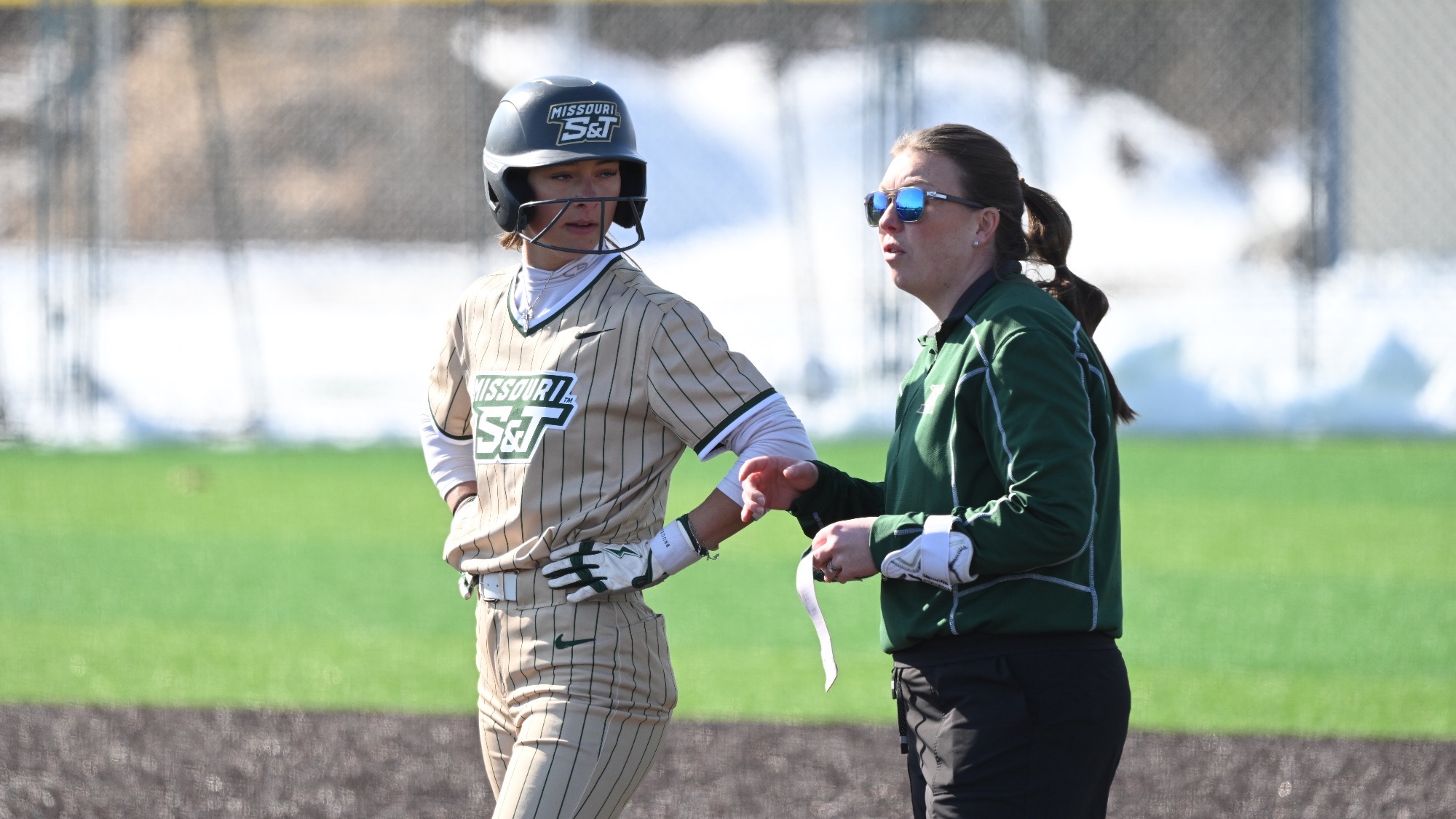 Missouri S&T softball player Kaylee LaChappell & head coach Summer Anagnostopoulos at first base during a game.