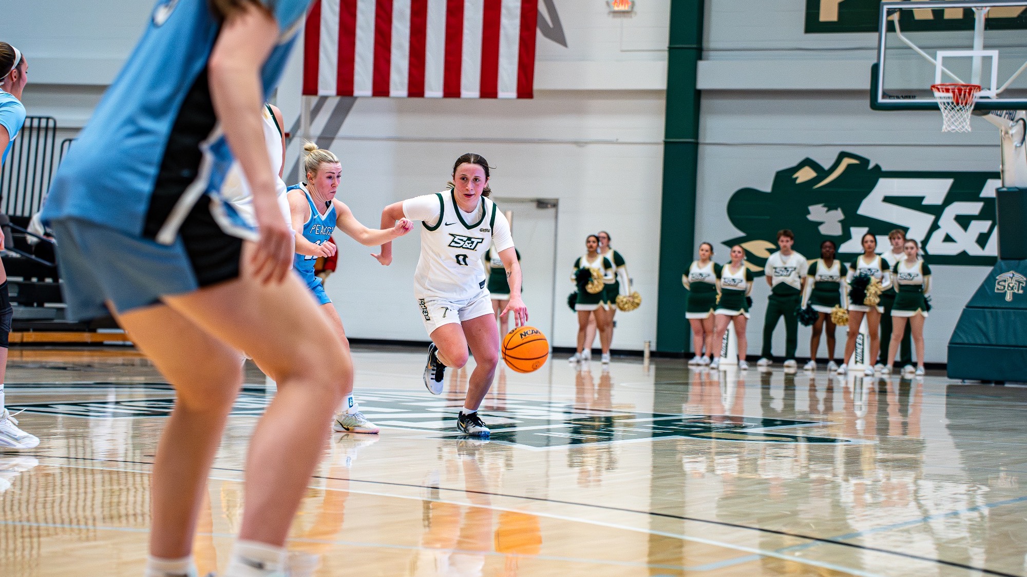 S&T women's basketball player Macy Marraccini dribbling the ball at the top of the key with Upper Iowa defender on her in Gibson Arena.