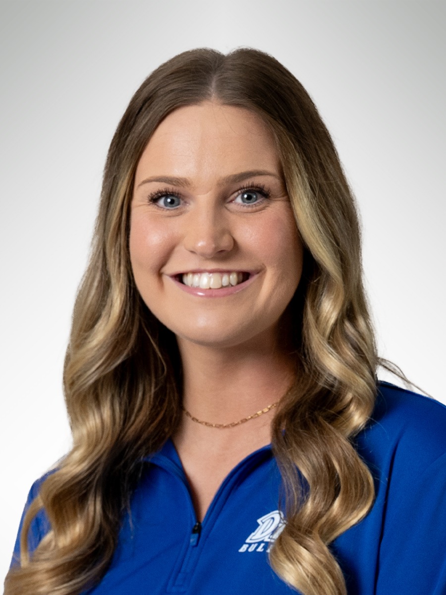 Professional headshot of Cooper Martin, photographed against a light gray studio background. She is smiling and wearing a royal blue quarter-zip athletic top. To the right of her image, green text reads “Cooper Martin” with the title “Women’s Volleyball Head Coach” displayed below. The Missouri S&T Miners logo appears in the upper right corner.