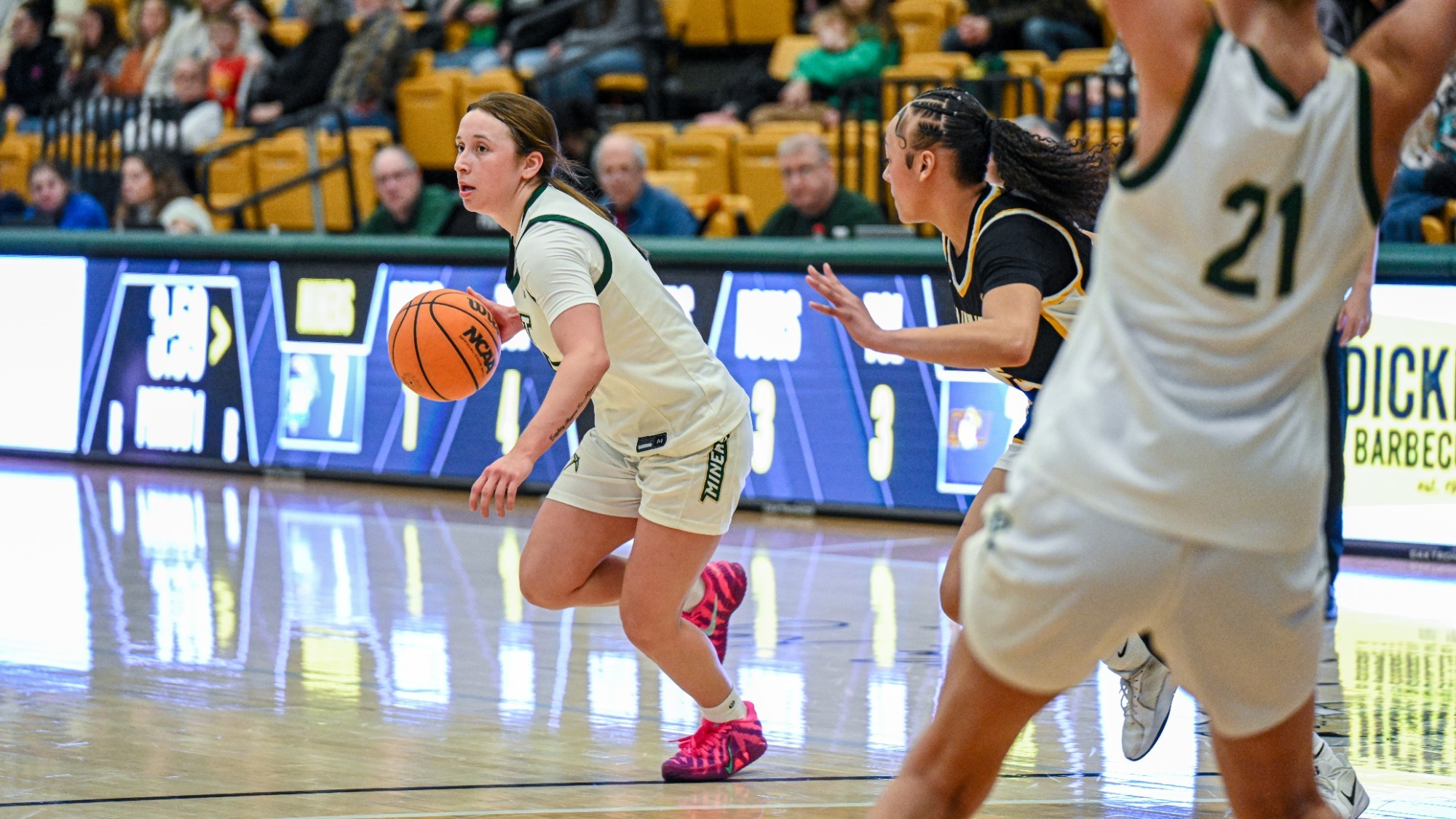 Missouri S&T women’s basketball player Macy Marraccini dribbles the ball in a white Miners jersey as a Quincy defender in a black jersey guards her during a game inside Gibson Arena.