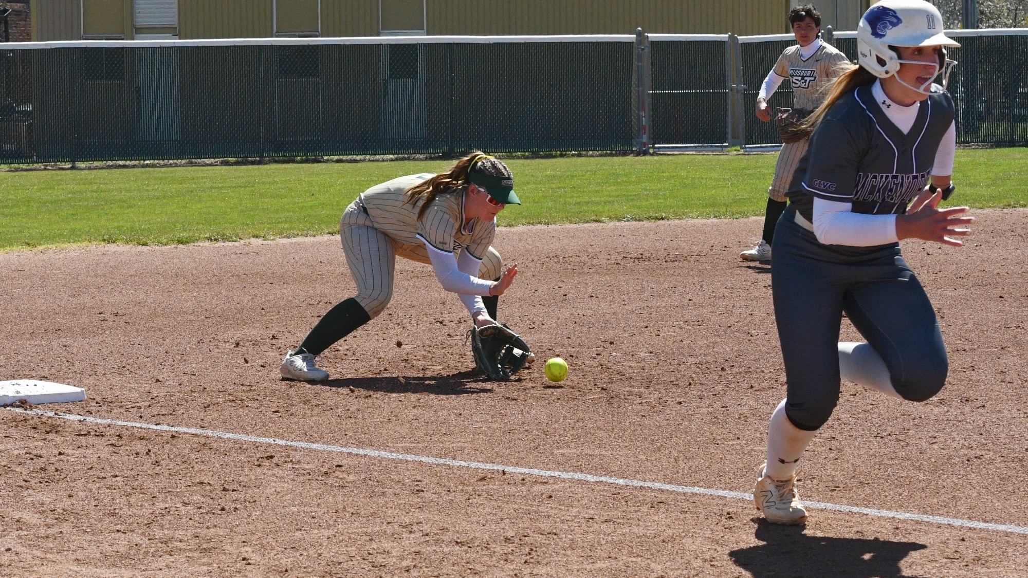 Missouri S&T third baseman Molly Fitzgerald fields a ground ball near third base while a McKendree runner sprints toward home plate during a softball game at Missouri S&T softball field.