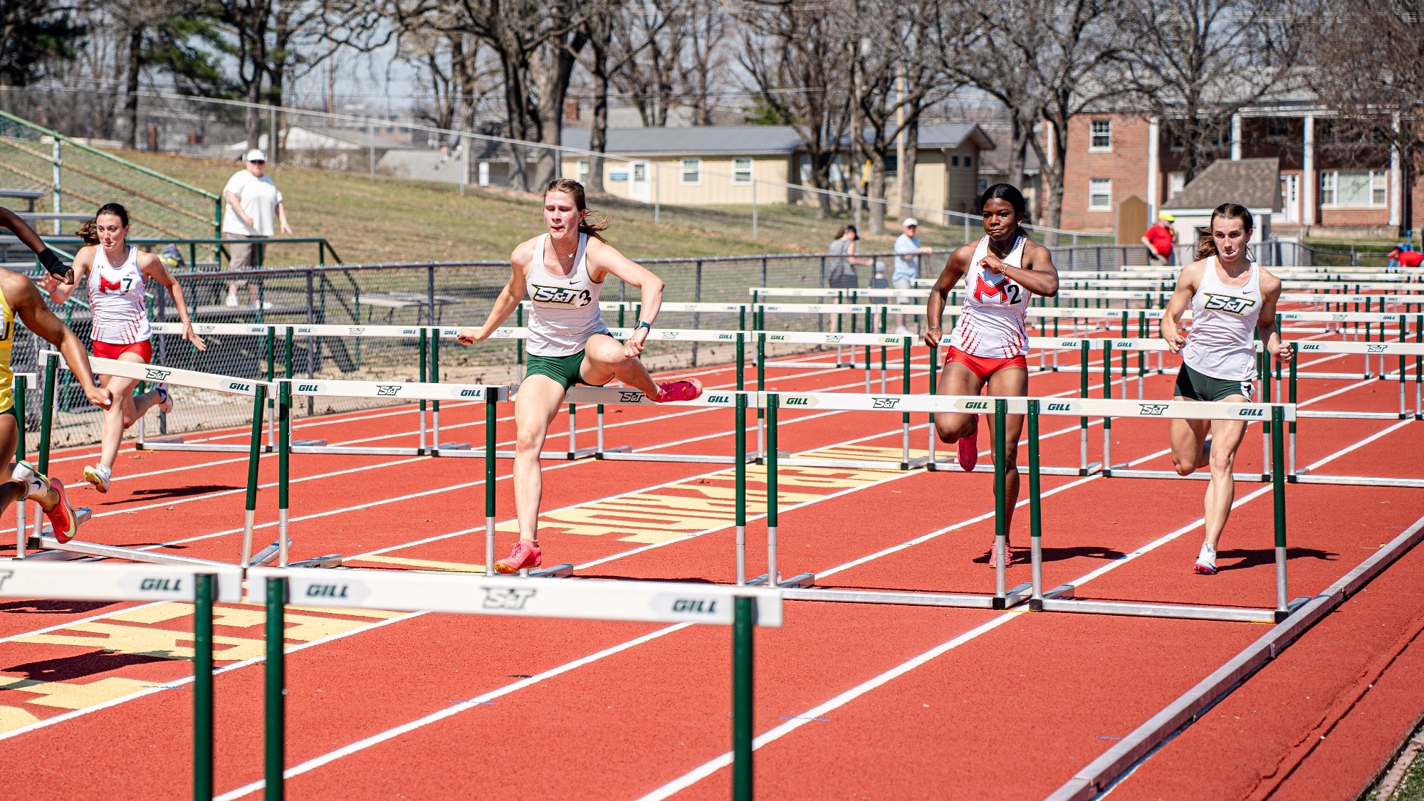 Missouri S&T hurdlers Maya Wright (left) and Mary Kimmerle (right) clear hurdles alongside a Maryville competitor during the 100-meter hurdles at the Miner Invitational.
