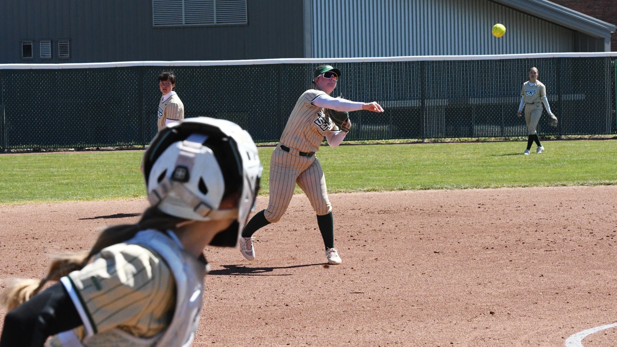 Missouri S&T third baseman Molly Fitzgerald throws across the infield as the catcher watches from behind the plate during a game at the S&T softball field.