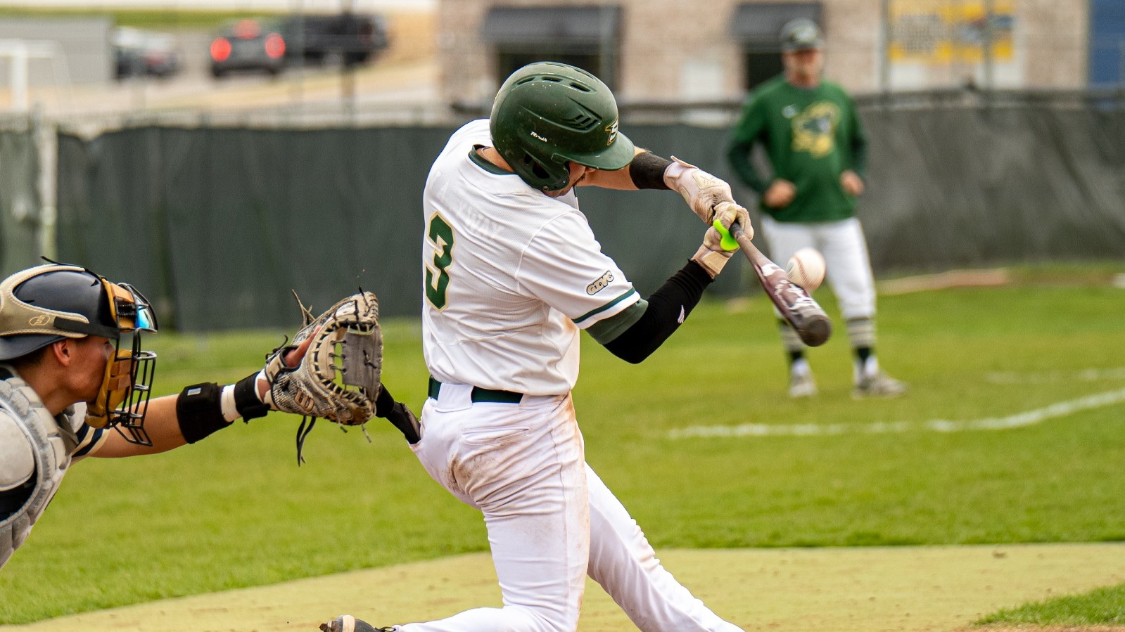 Photo of Missouri S&T baseball player Keaton Scott midswing and making contact with the ball during an at bat. He is wearing a white jersey and green batting helmet.