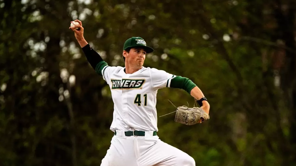 Missouri S&T baseball pitcher Jack Manninen photographer while throwing a pitch on the mound. His right arm is raised and he is wearing a white jersey either green trim