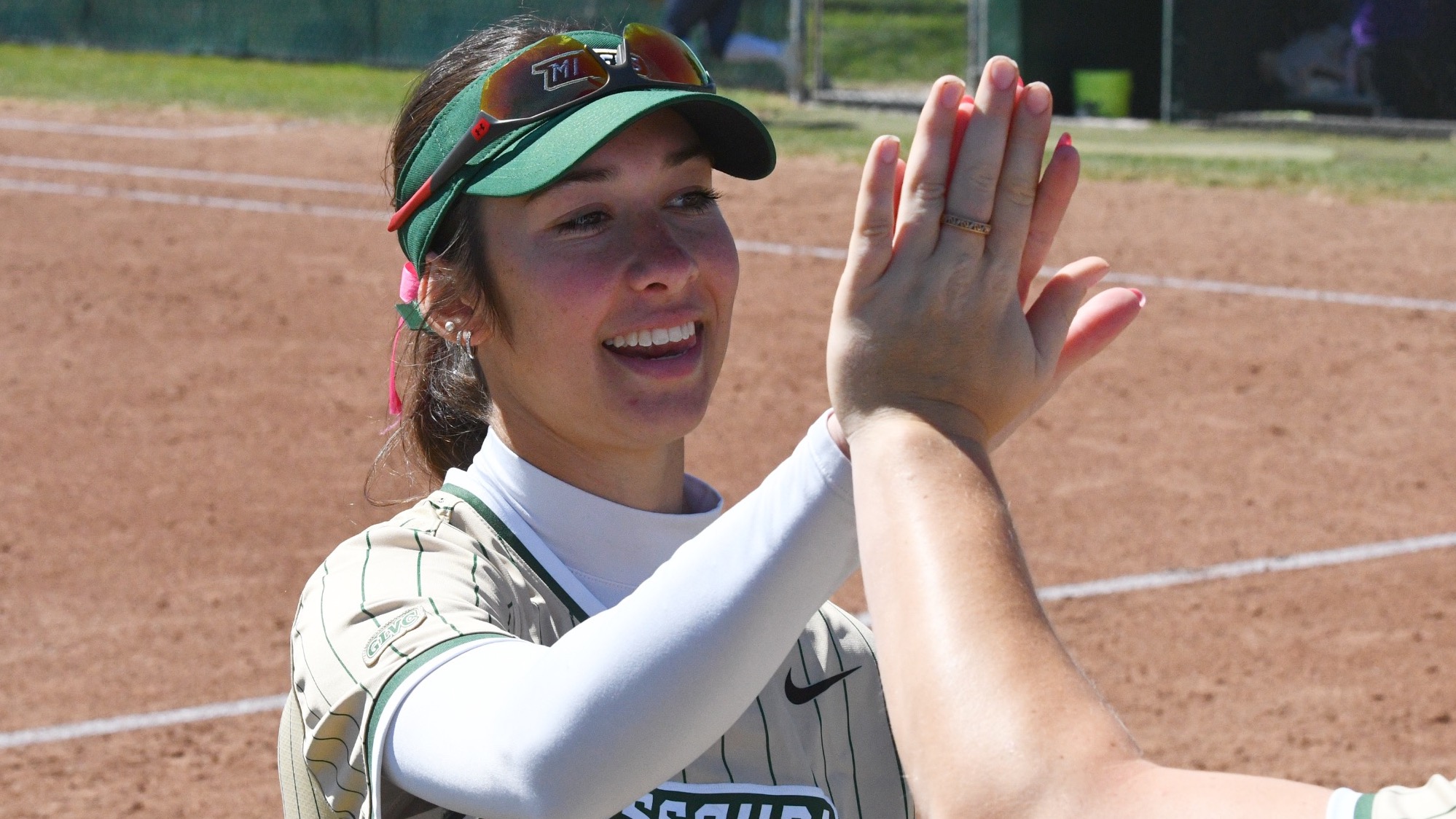 Missouri S&T softball player Autumn Trower smiling while giving a high five to her teammate during a game at the Missouri S&T softball field.