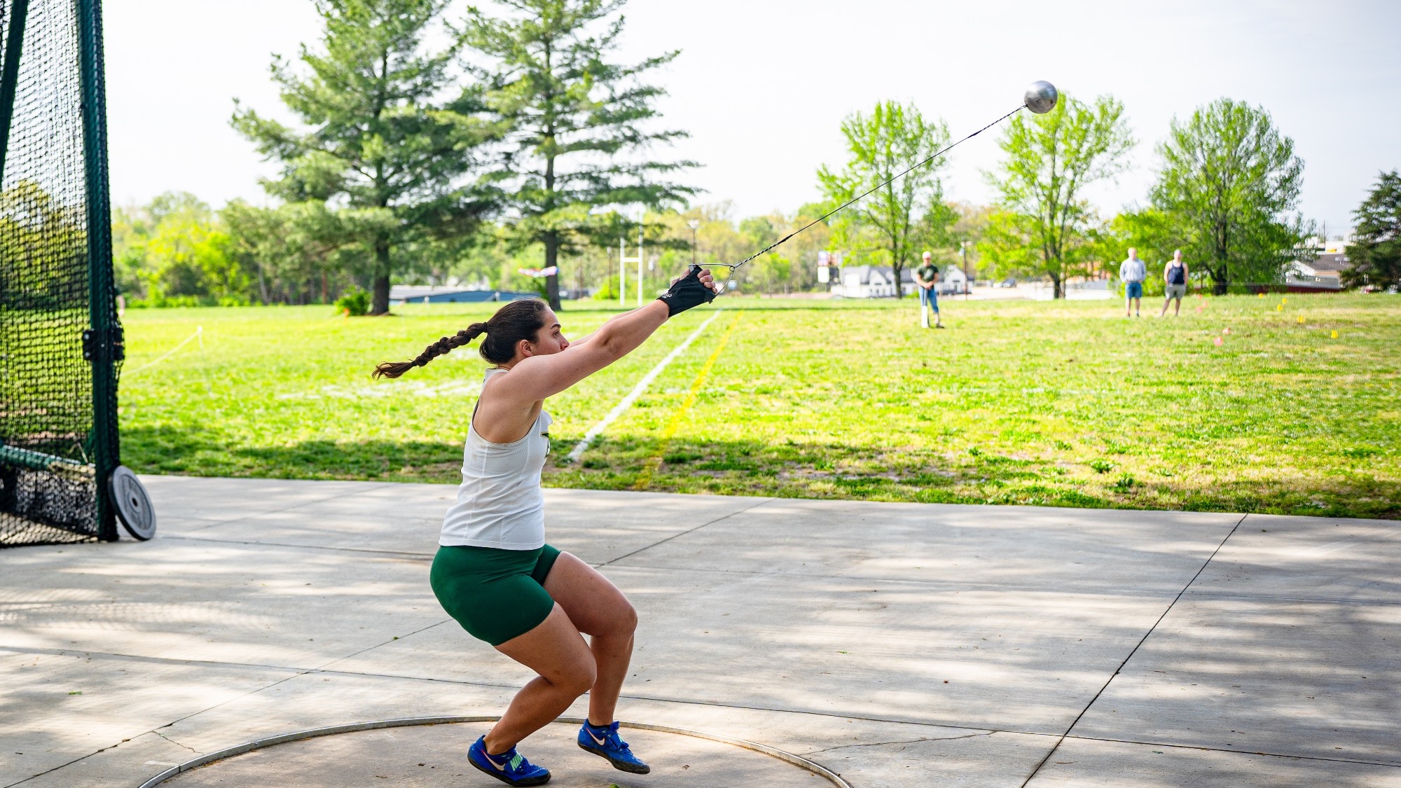 Sydney Morris of Missouri S&T competes in the weight throw at the Dewey Invitational, spinning inside the throwing circle as the weight extends outward, with spectators watching in the background.