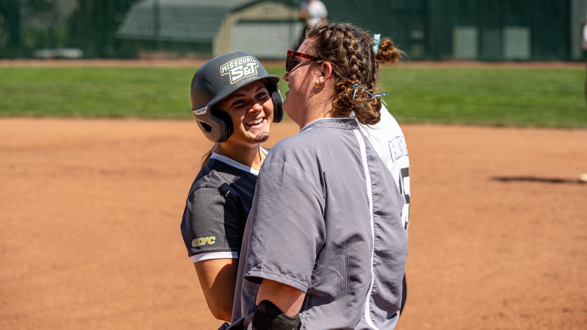 Morgan Williams of Missouri S&T softball smiles while talking with student assistant coach Sydney Anderson during a game at the S&T softball field.
