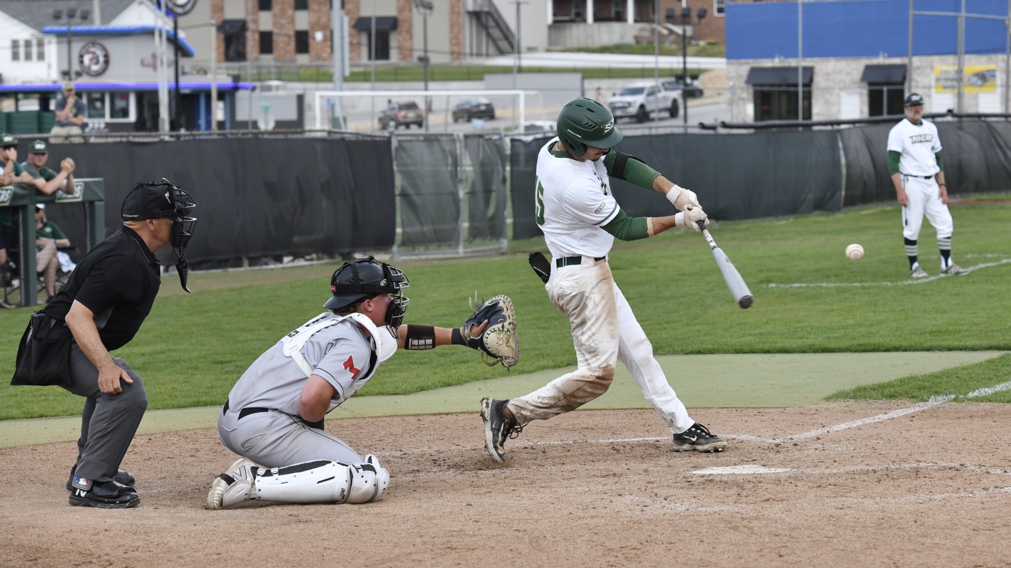  Missouri S&T Baseball's Garrett Meyer swings the bat and makes contact with the ball during an at bat in a game against Maryville at the Ballpark at S&T. He wears a white uniform with green trim.