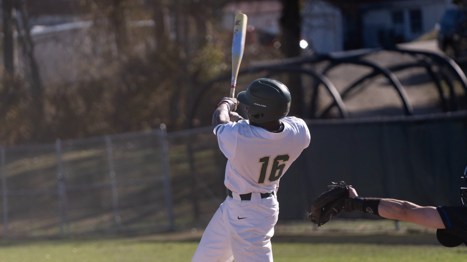 Missouri S&T Miners baseball player Bricen Smith follows through on a swing during a game, wearing a white uniform with number 16 as a catcher and umpire are positioned behind home plate