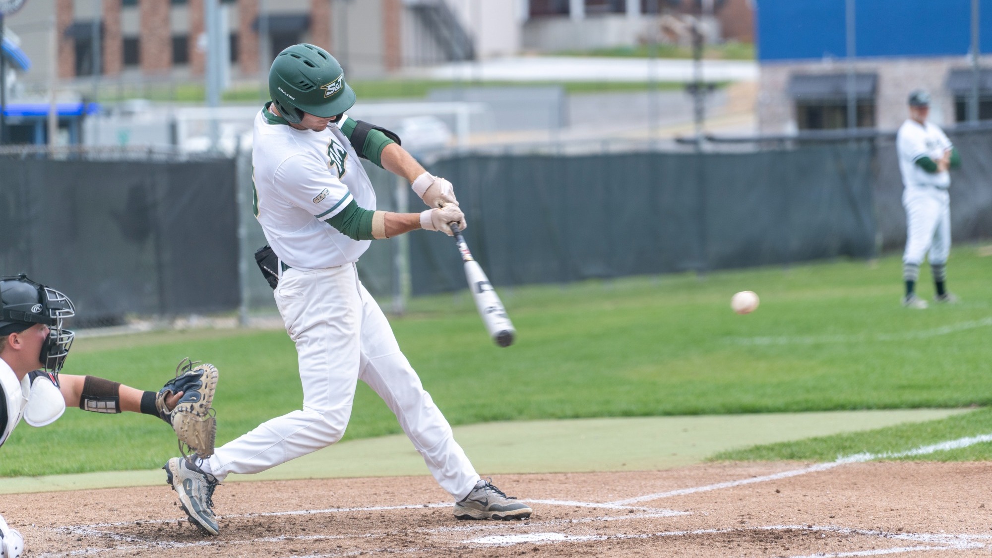 Garrett Meyer photographed swinging during an at bat. He is wearing a white uniform with green trim and a green batting helmet.