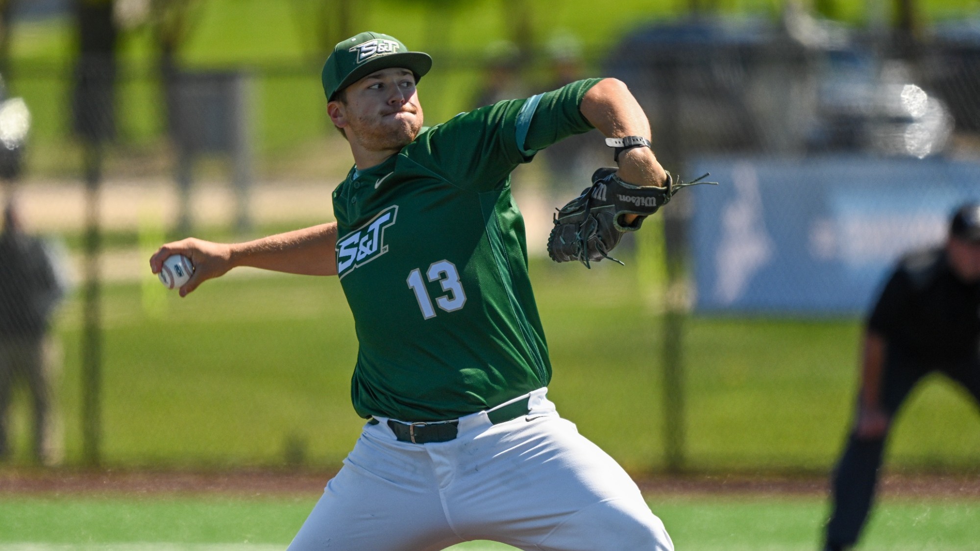 Dylan Bates of Missouri S&T Baseball photographed mid-pitch. He is wearing a green S&T uniform and matching hat with white pants.