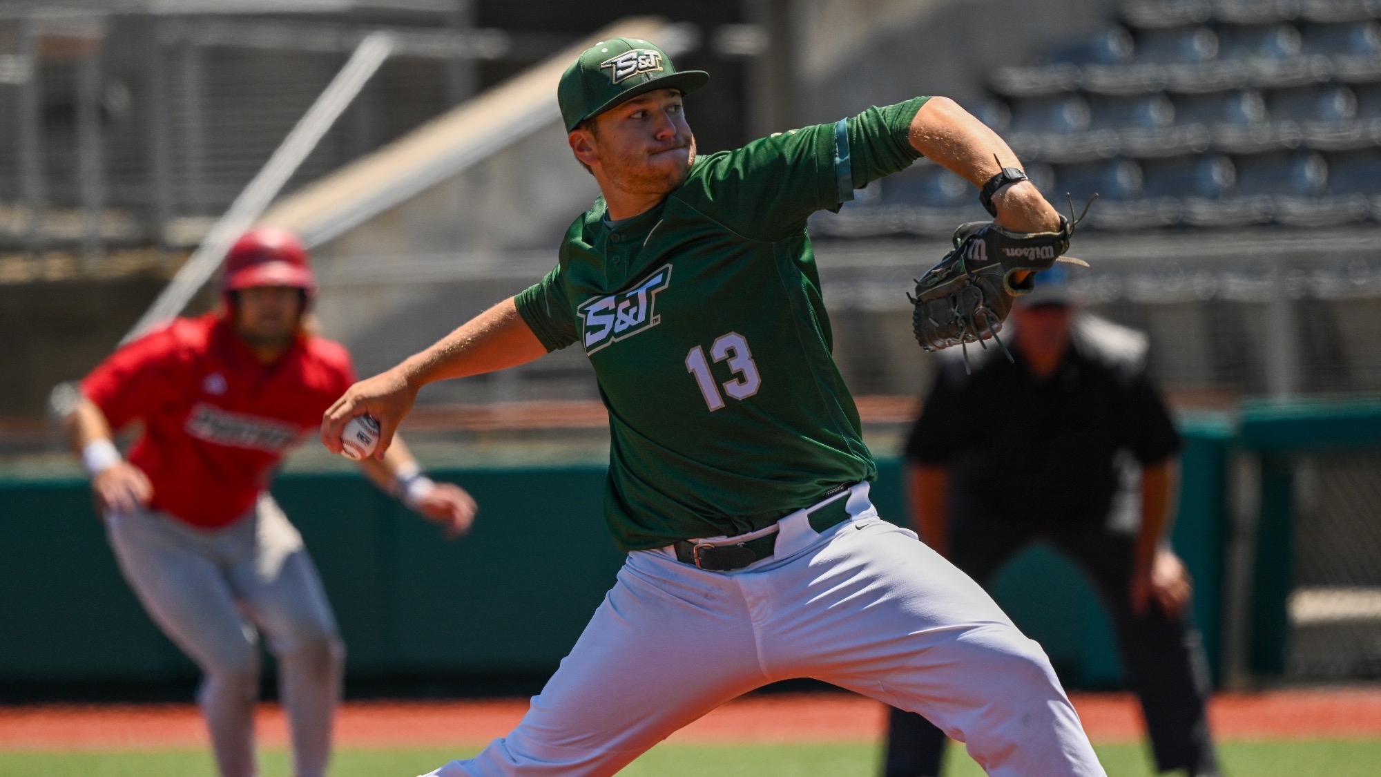 Missouri S&T baseball player Dylan Bates delivers a throw across the infield during a game while a runner in a red jersey looks to advance in the background.