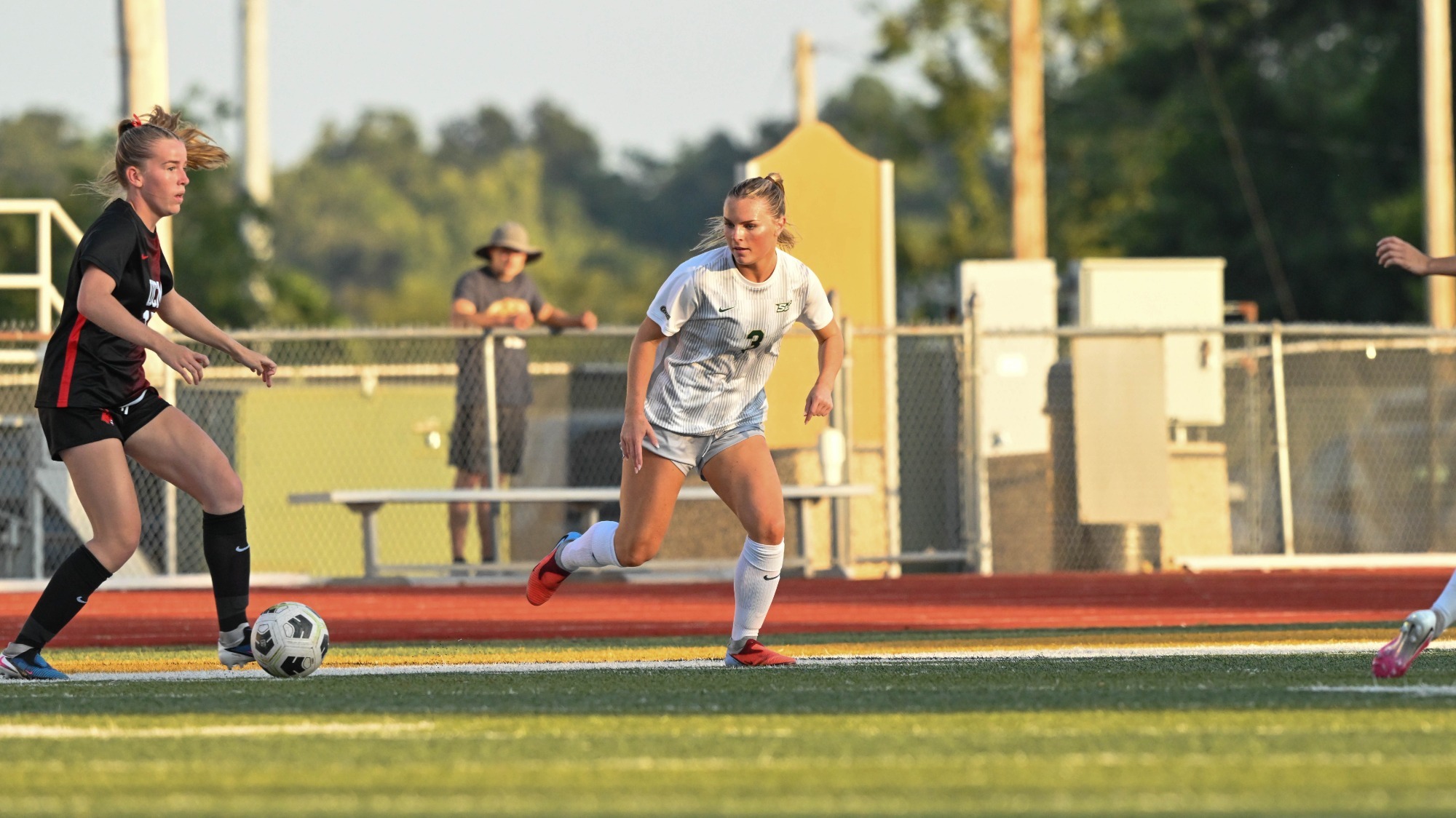 Jenna Marti of Missouri S&T Women's Soccer photographed wearing a white and gray uniform while watching an opponent bring the ball up field