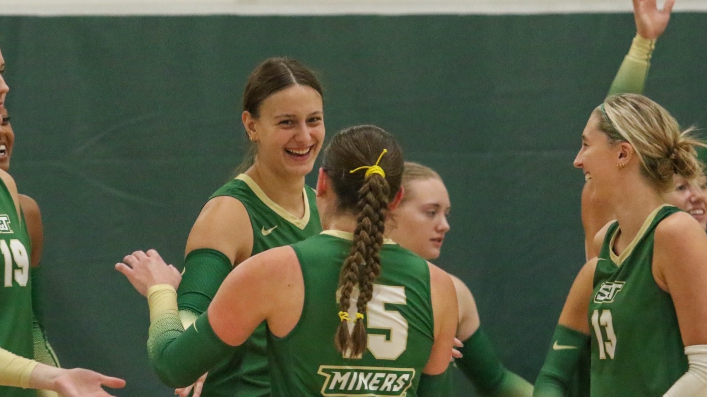 Women’s volleyball team photographer celebrating while wearing green uniforms