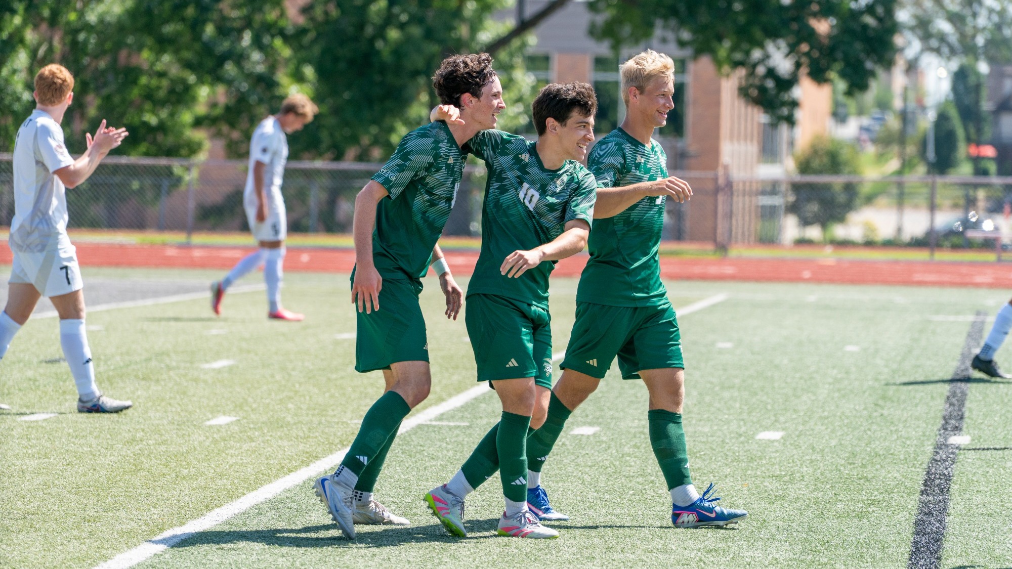 Mike Banasik, Caleb Lepant and Joao Vieira photographed wearing green uniforms and celebrating together after Lepant scored a goal
