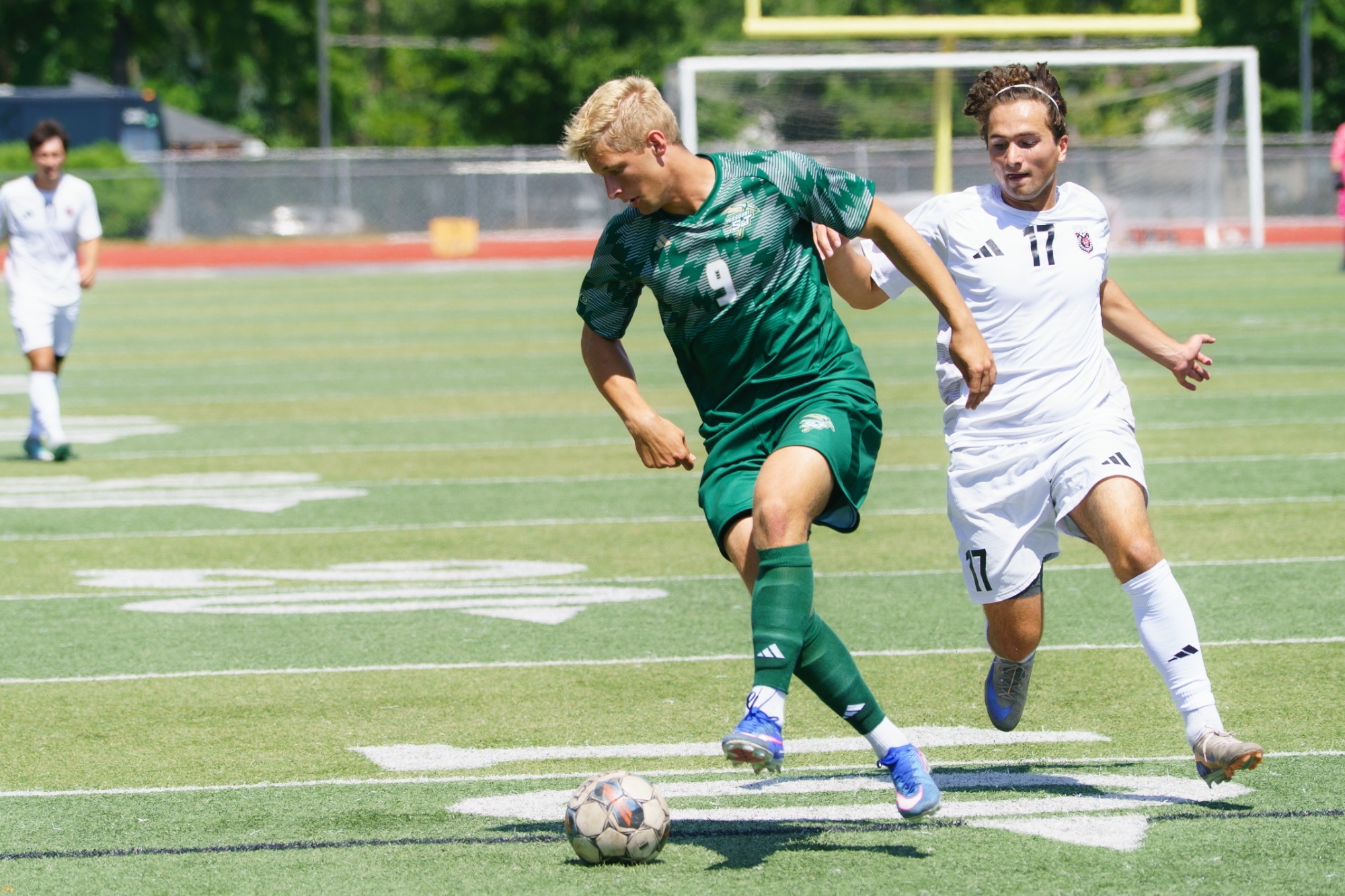 Mike Banasik in a green jersey dribbling the ball away from a Davenport defender in a white jersey. 