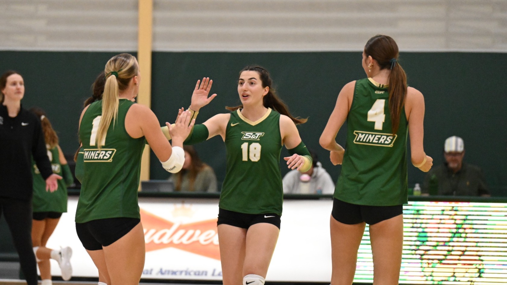 Selin Ozdemir of Missouri S&T Women's Volleyball wearing a green uniform and going to high five a teammate during a match in Joplin, Missouri