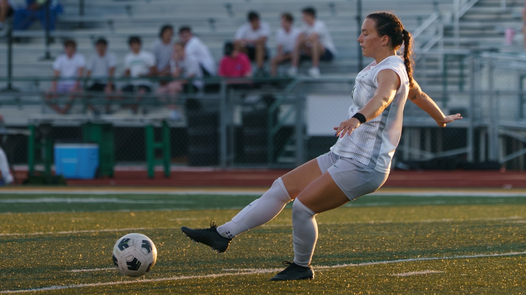 Savannah Tully of Missouri S&T women's soccer photographed kicking the soccer ball while wearing a white and gray kit during a home match
