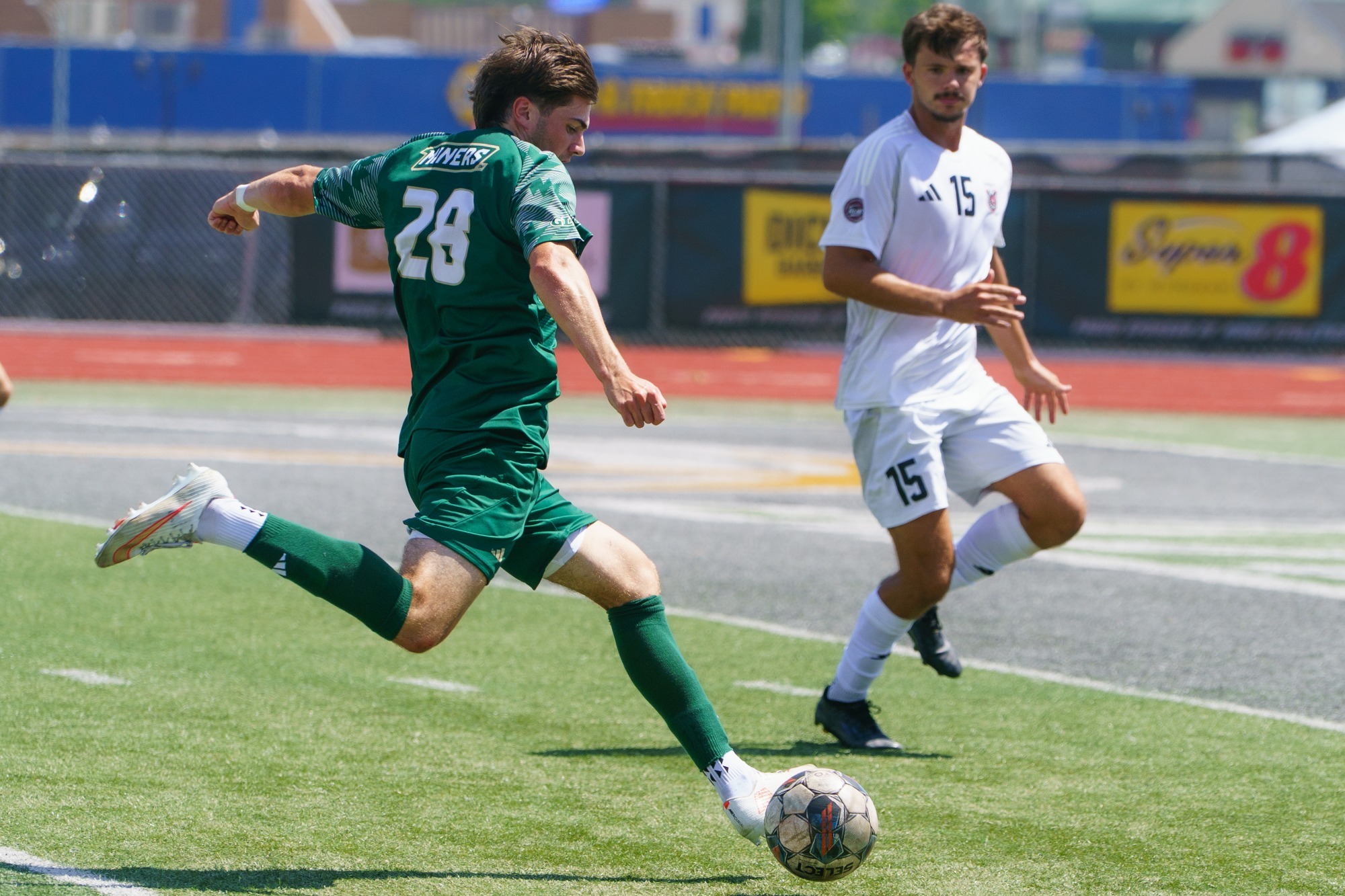 Smith Russel for Missouri S&T men's soccer in a green jersey and green shorts, offensively and aggressively attacking the ball. 