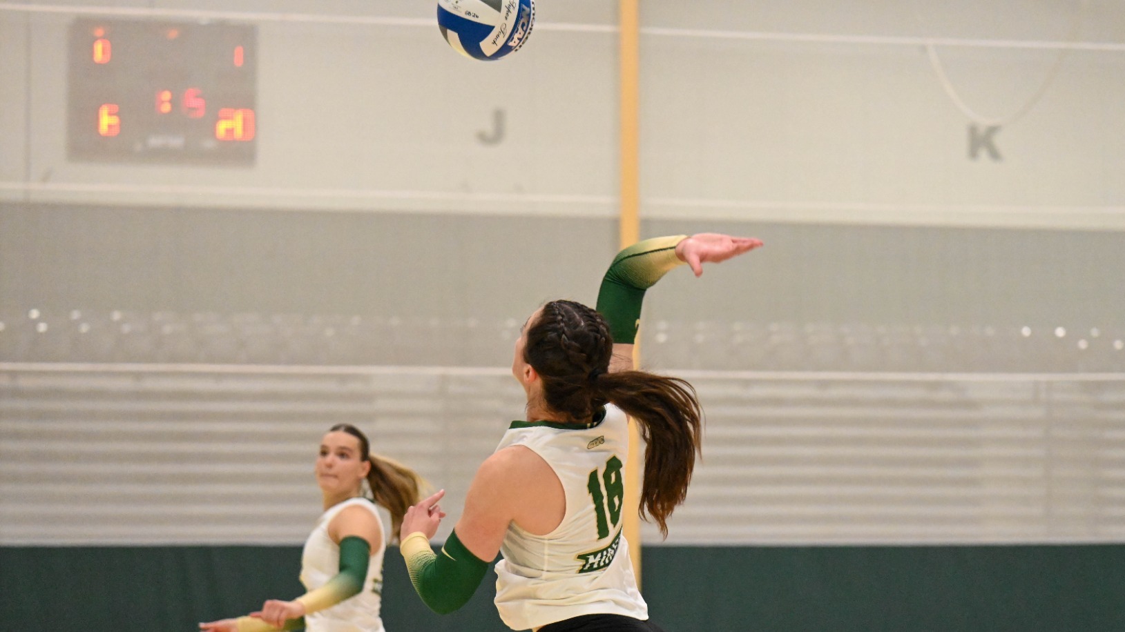 Selin Ozdemir of Missouri S&T Women's Volleyball photographed attacking the volleyball during a match at MSSU. She is wearing a white S&T volleyball uniform